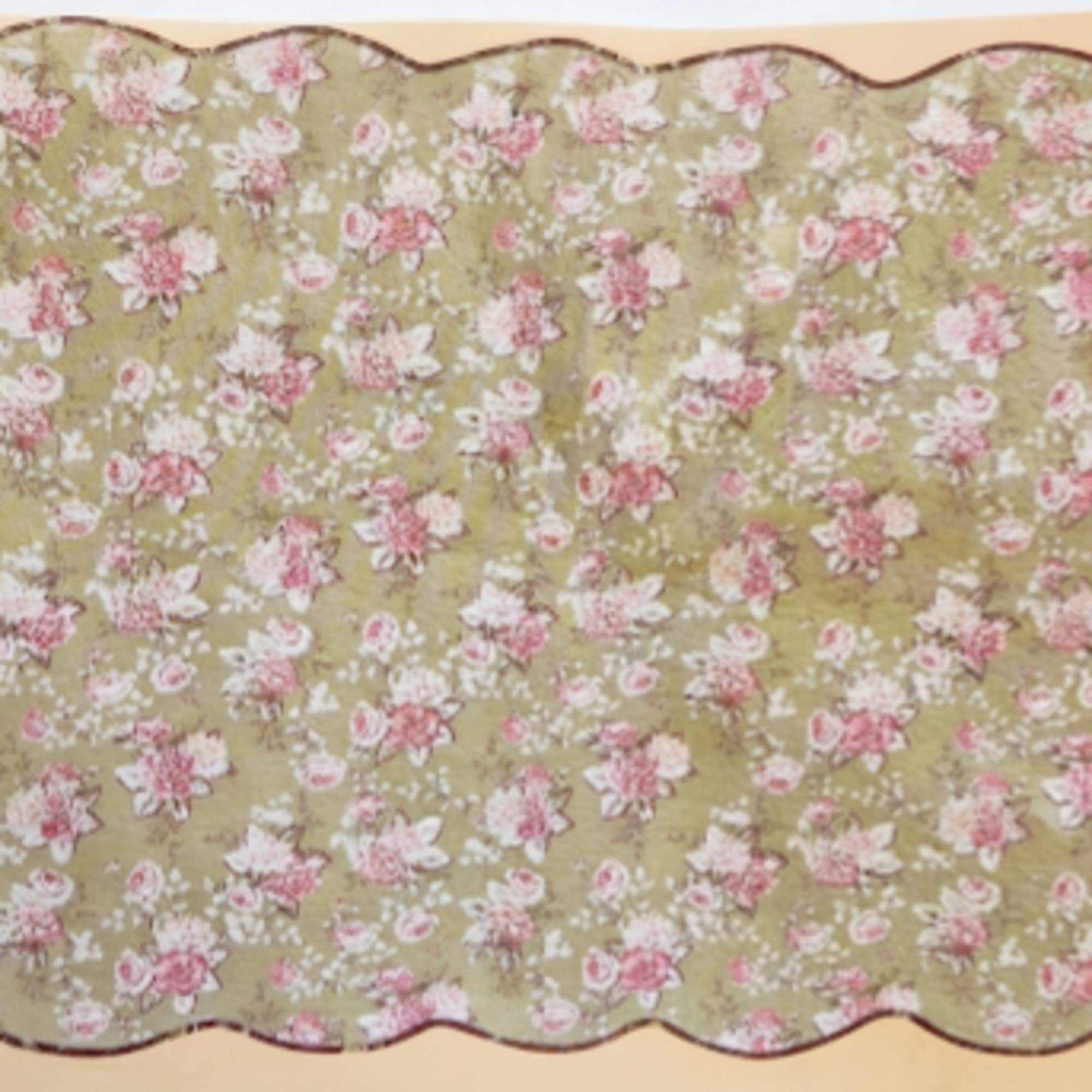 Floral-patterned scalloped fabric in pink and white on a green background