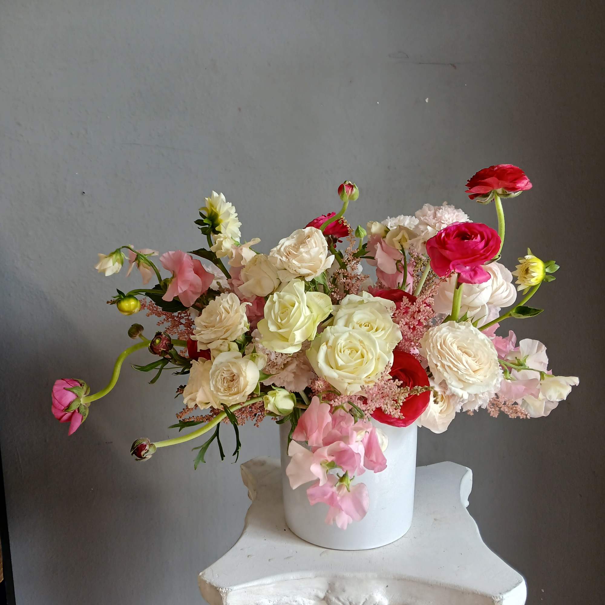 Mixed pink and white flowers arranged in a white vase