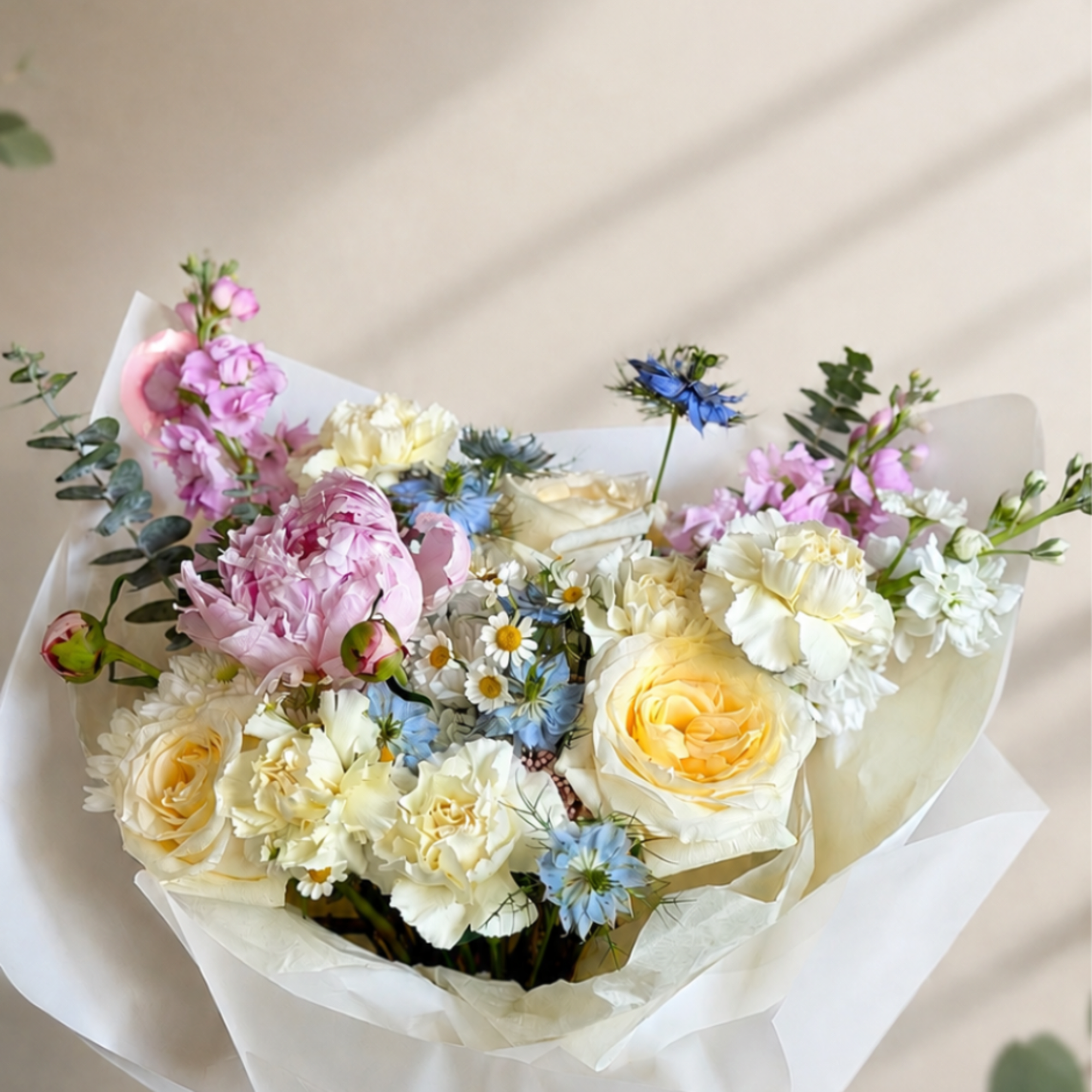 Large blush peonies paired with cream and pale yellow roses create a