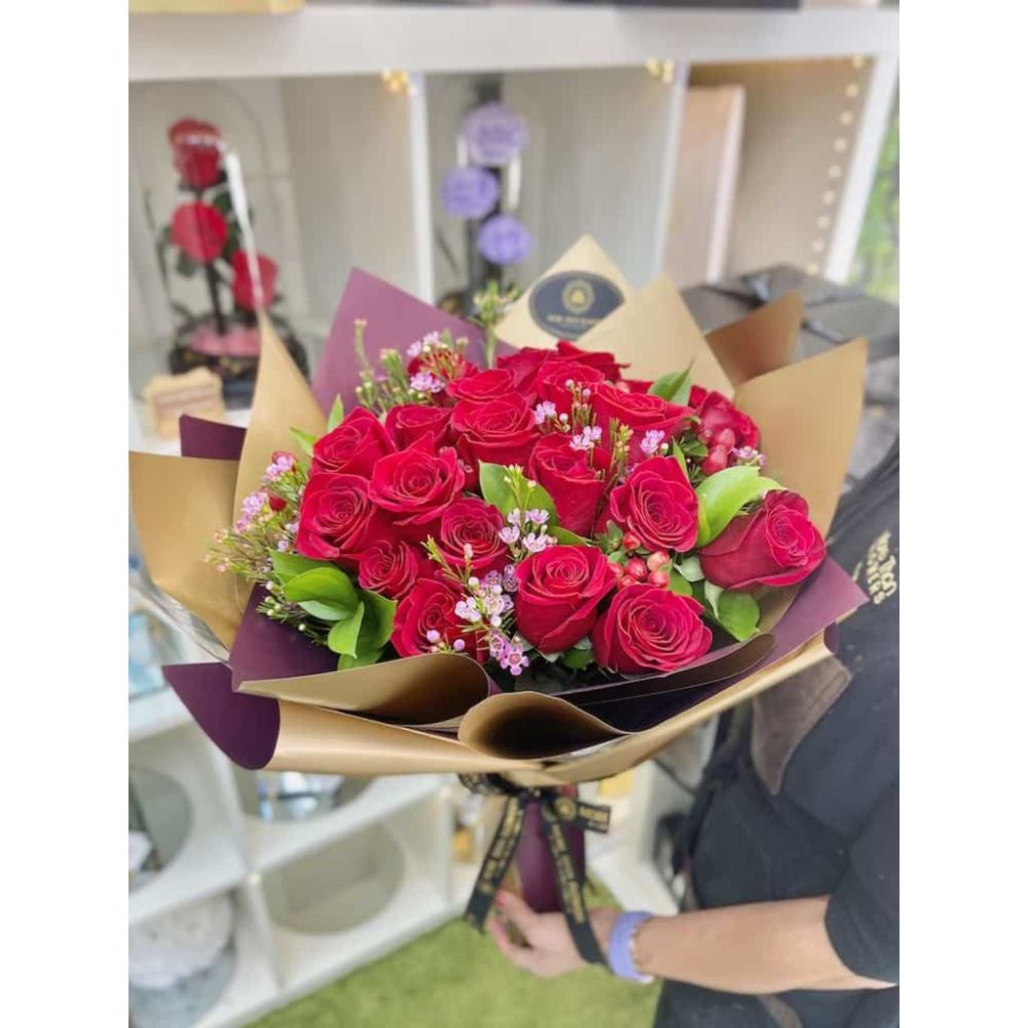 Hand-tied bouquet of red roses with pink filler flowers wrapped in gold and burgundy paper