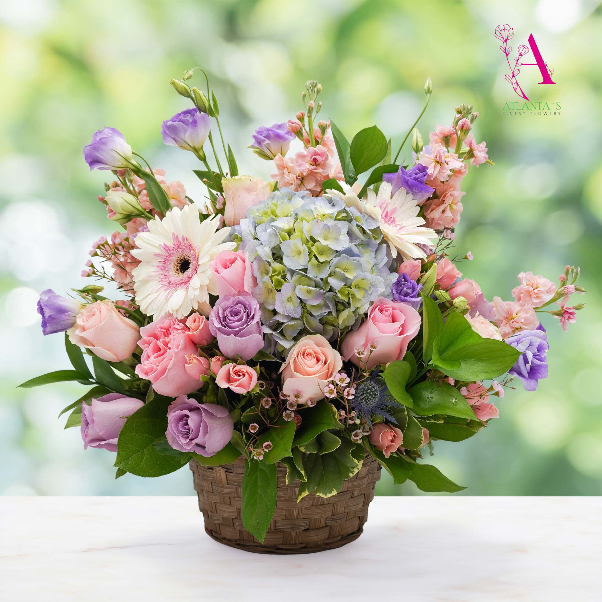 Basket arrangement of pink and lavender roses with hydrangea and gerbera daisies