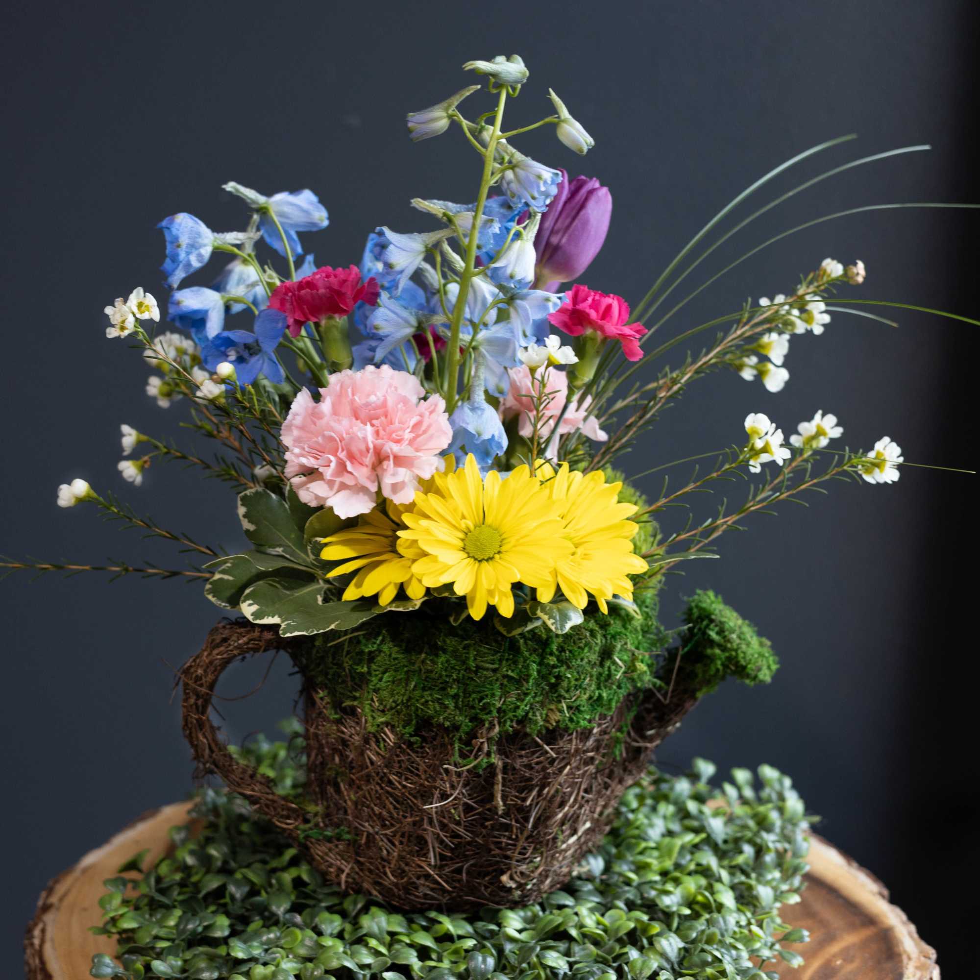 Colorful mixed flower arrangement in a moss-covered basket