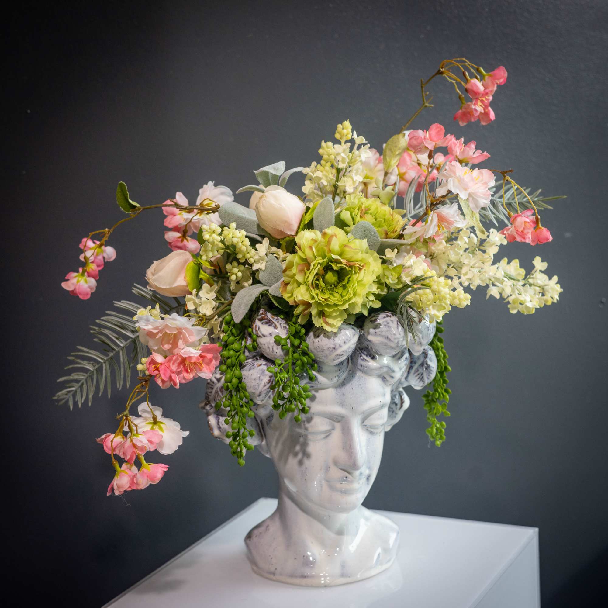 Floral arrangement on a white bust vase with pink and cream flowers