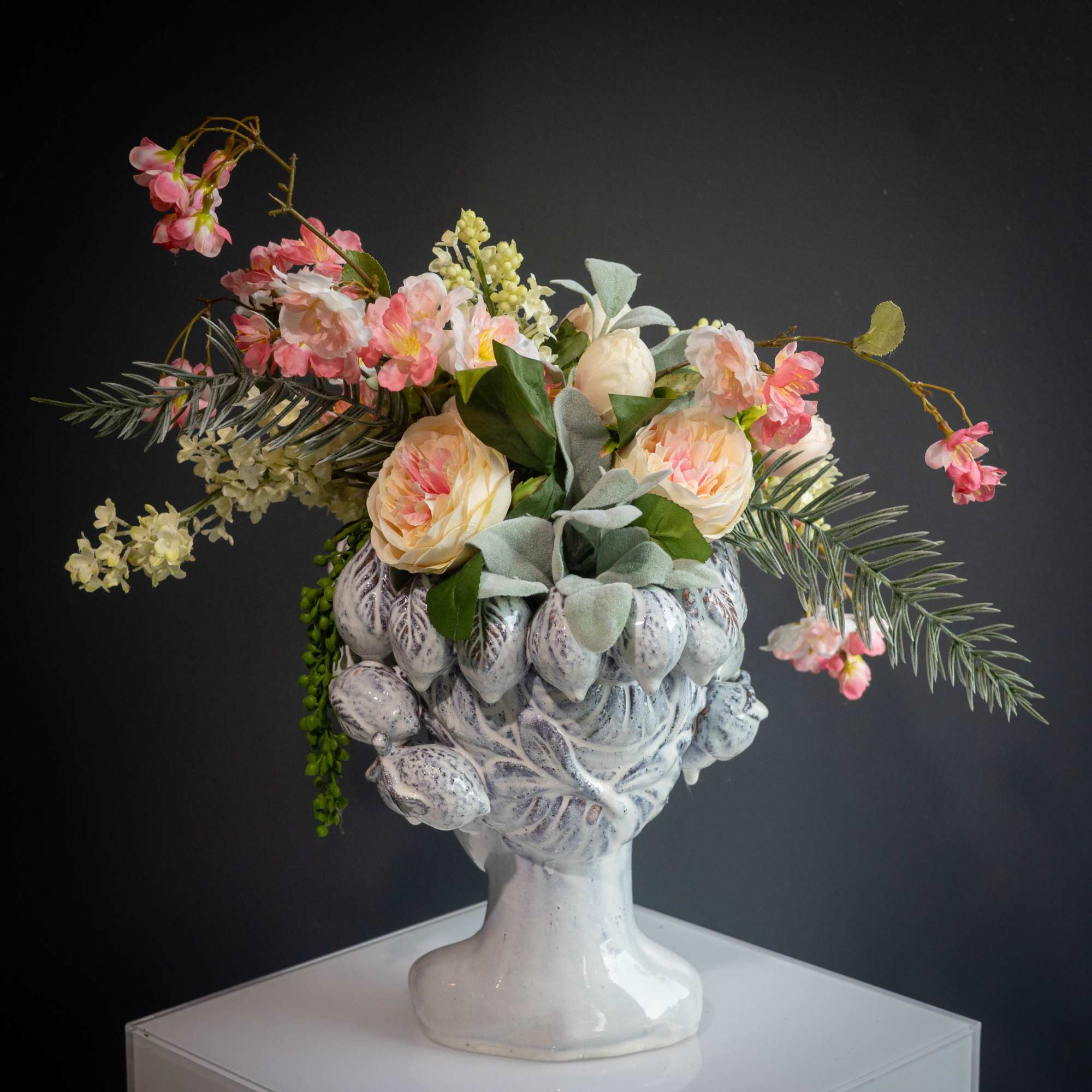 Floral arrangement in a white sculpted vase with pink and cream blooms