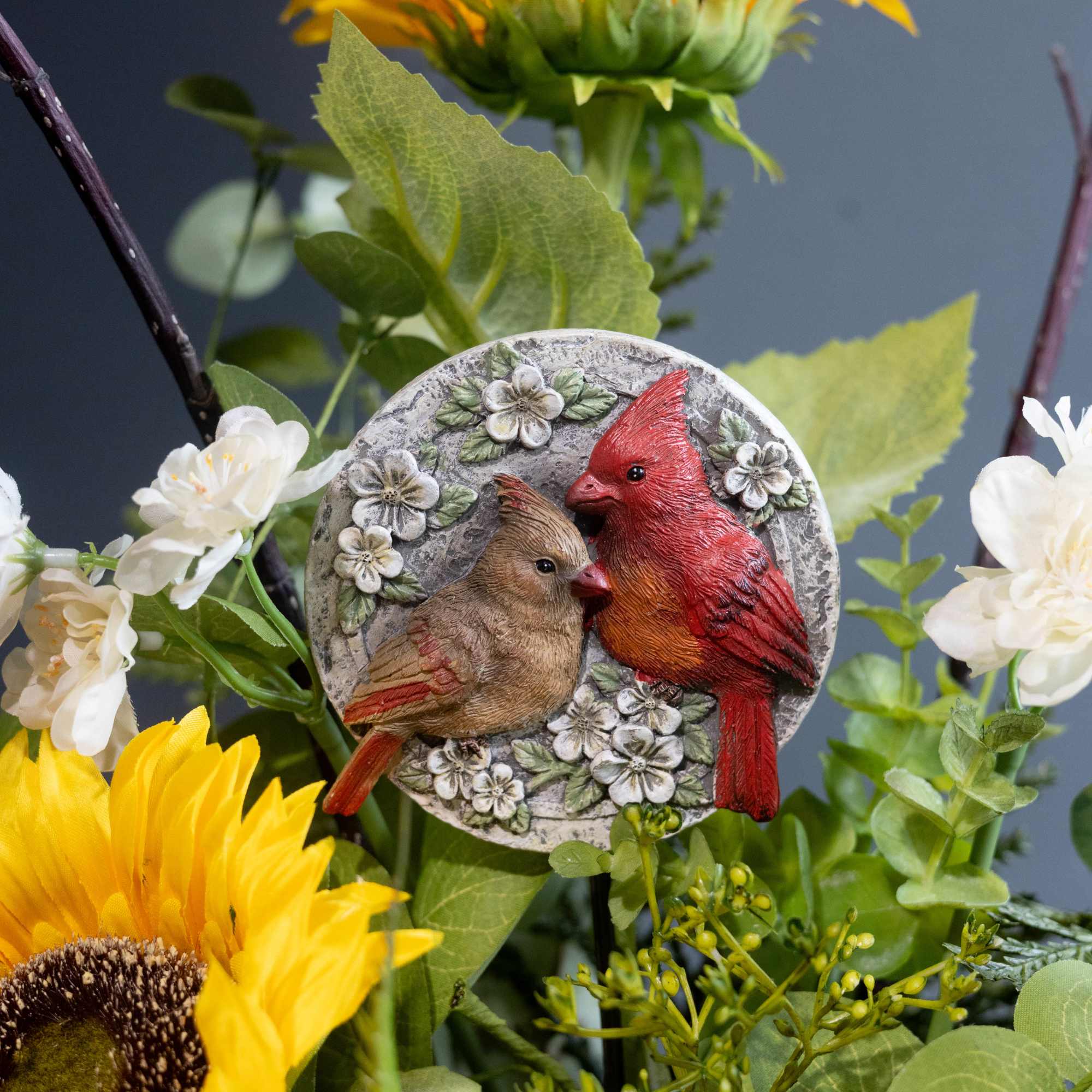 Sunflowers and white blossoms around a decorative bird ornament