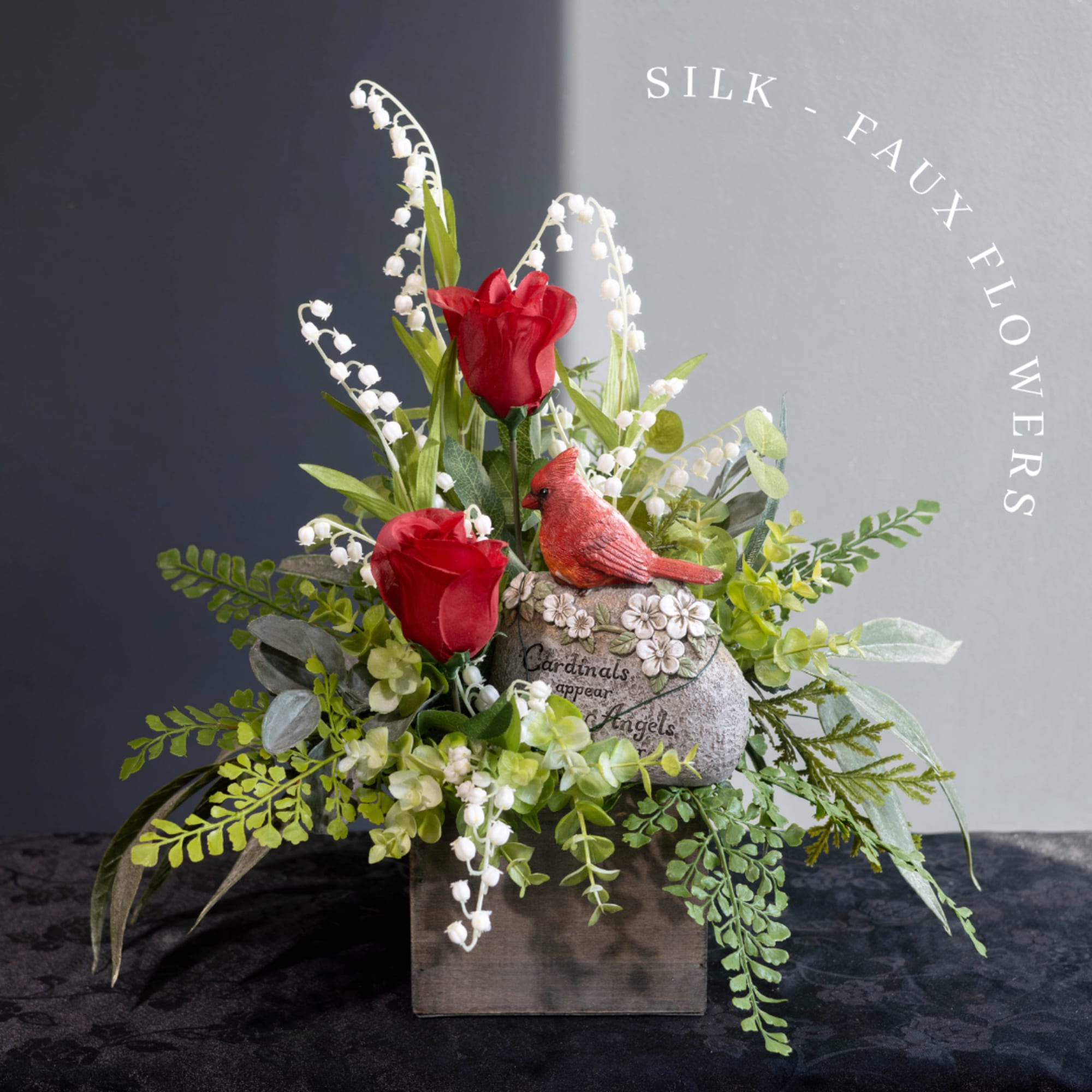 Silk red roses and white lily-of-the-valley in a rustic box with a cardinal figurine