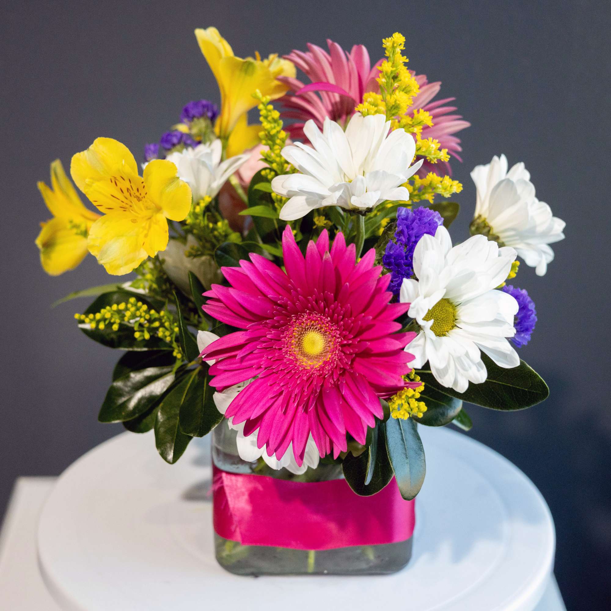 Mixed bouquet with pink, white, yellow, and purple flowers in a glass vase