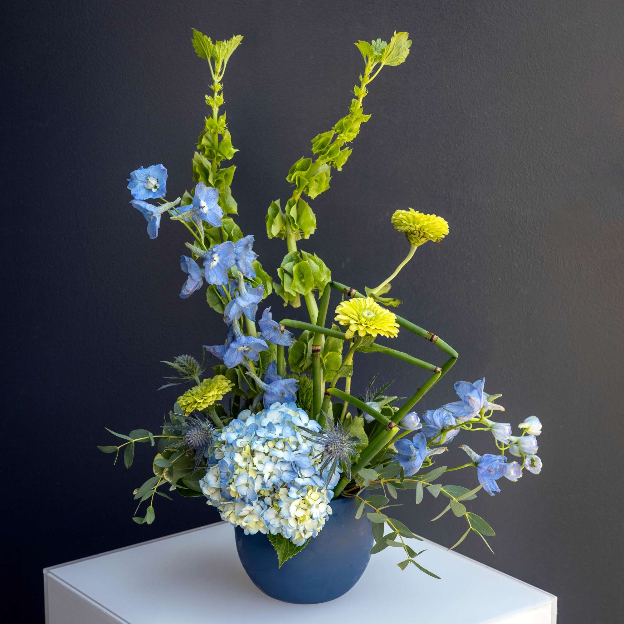 Blue and yellow floral arrangement in a blue vase