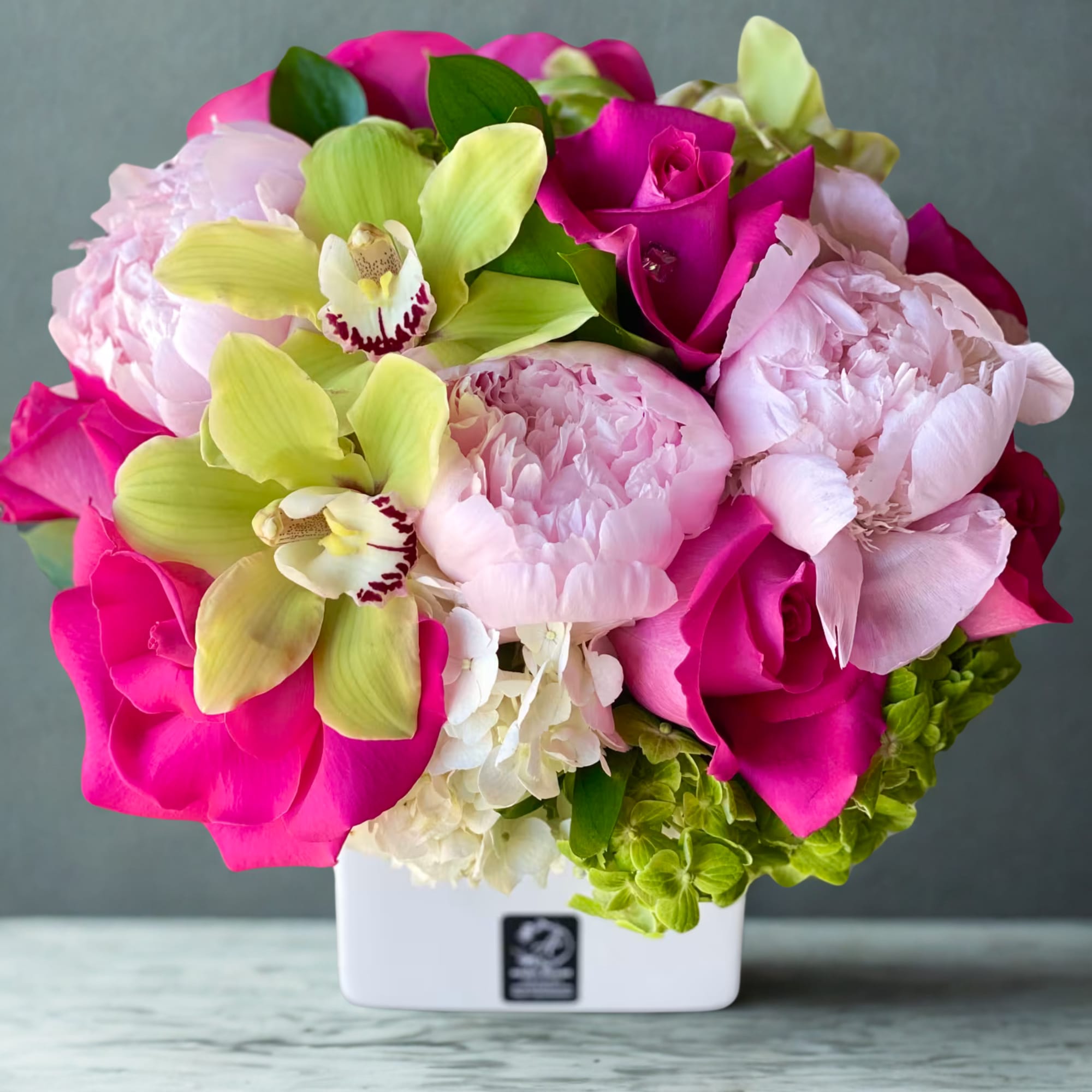 Pink and lime floral arrangement in a white square vase