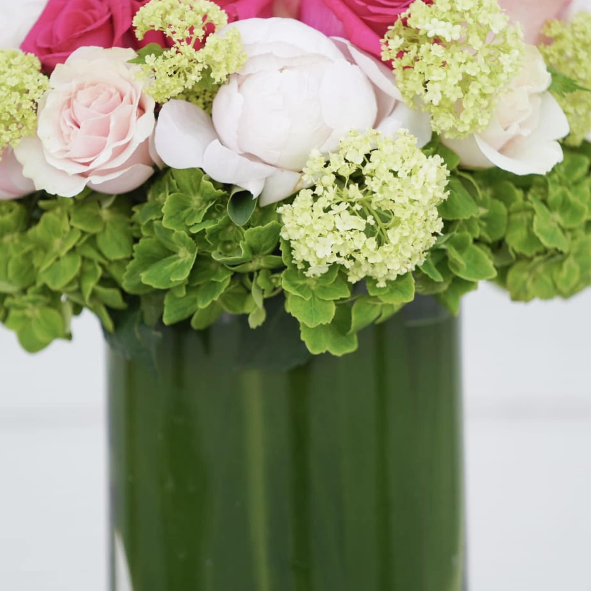 Pink and white roses arranged in a tall glass vase