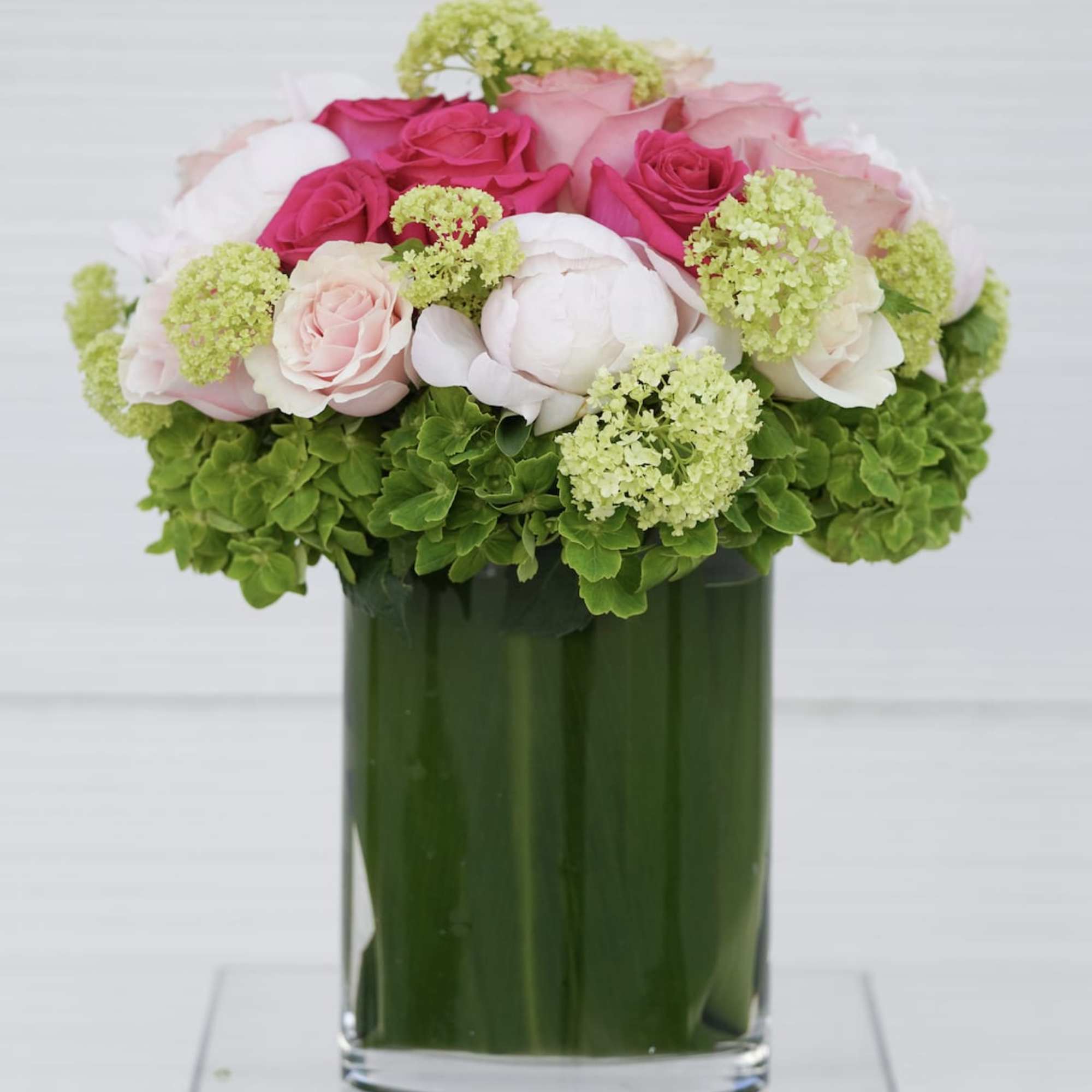 Pink and white roses arranged in a green glass vase