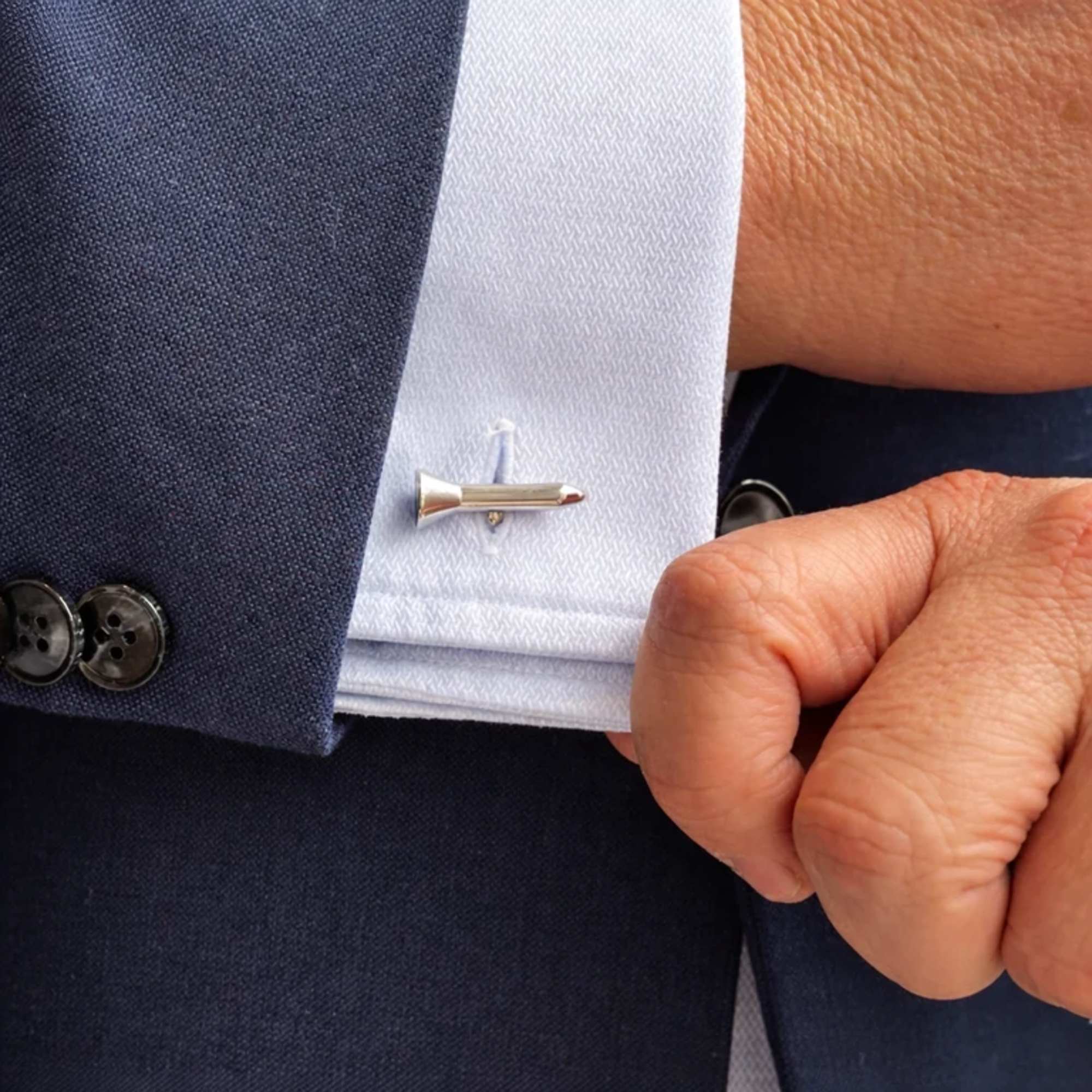 Suit jacket with a silver tie clip and white shirt cuff