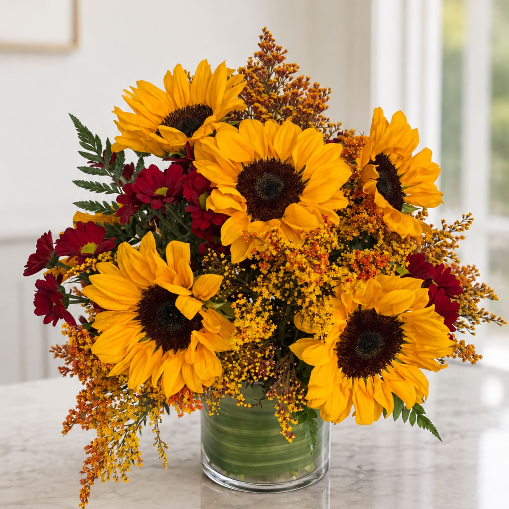 Sunflower and burgundy daisy arrangement in a clear glass vase