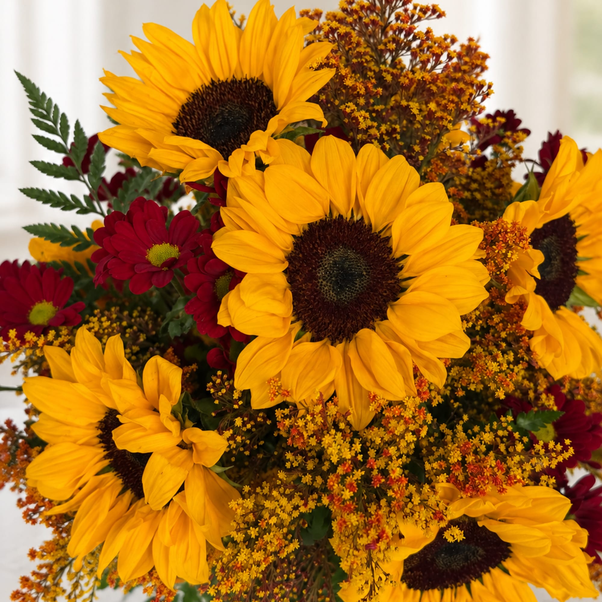 Bouquet of yellow sunflowers and red daisies with autumn filler