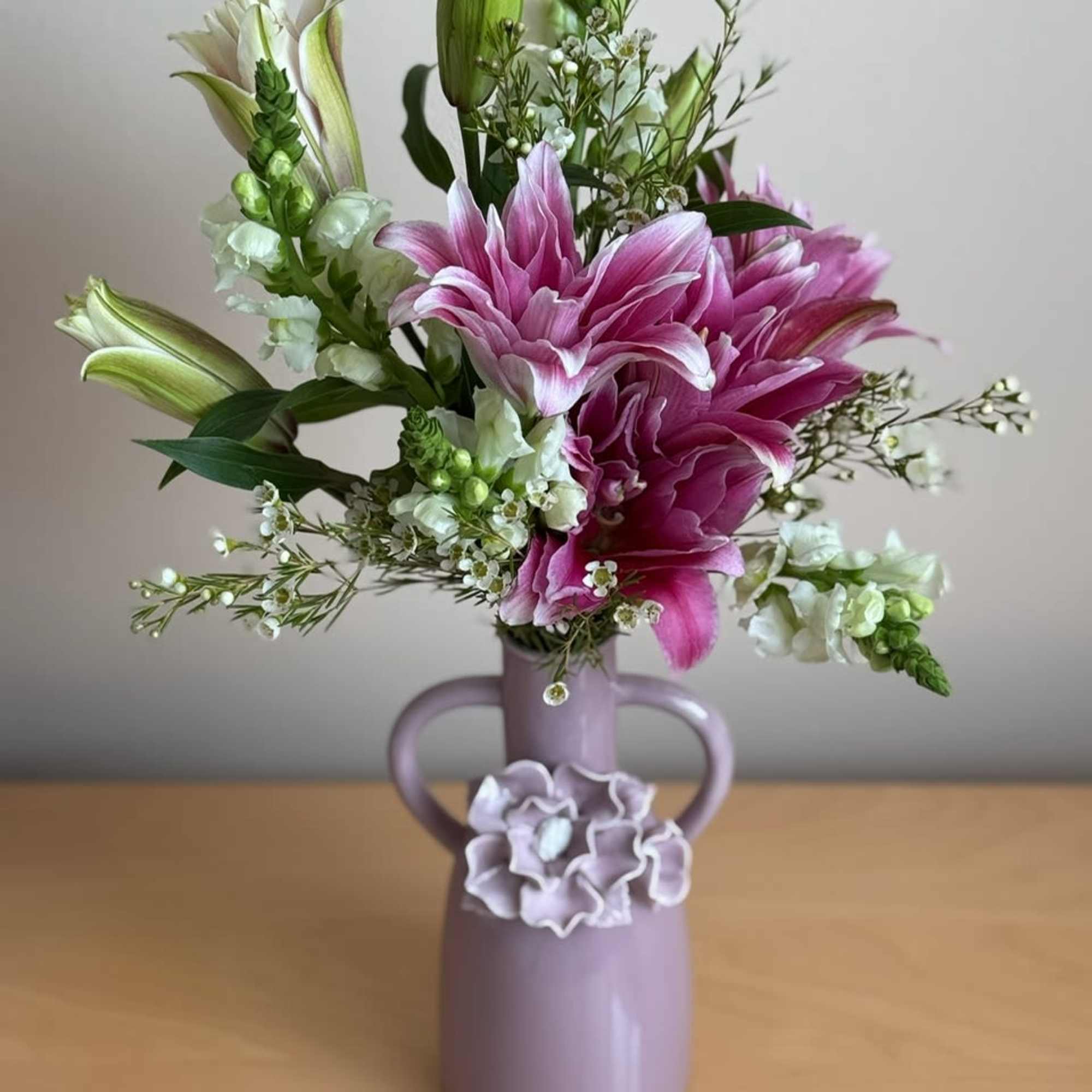 Pink lilies and white flowers in a lavender vase