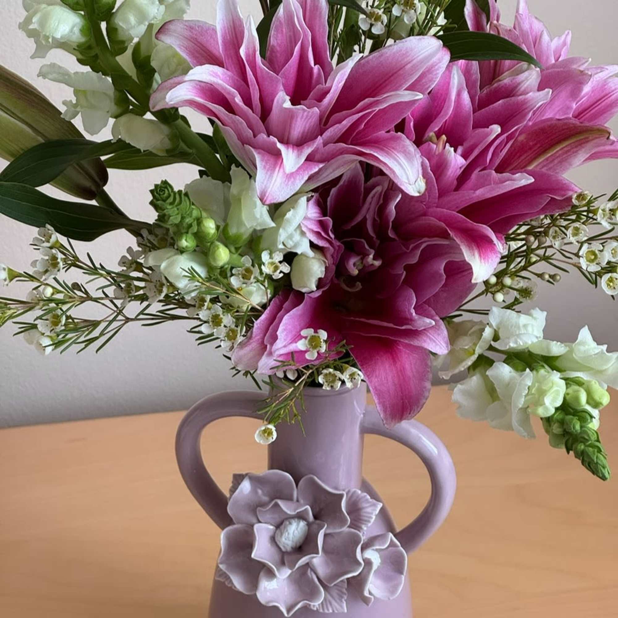 Pink lilies and white snapdragons in a lavender vase