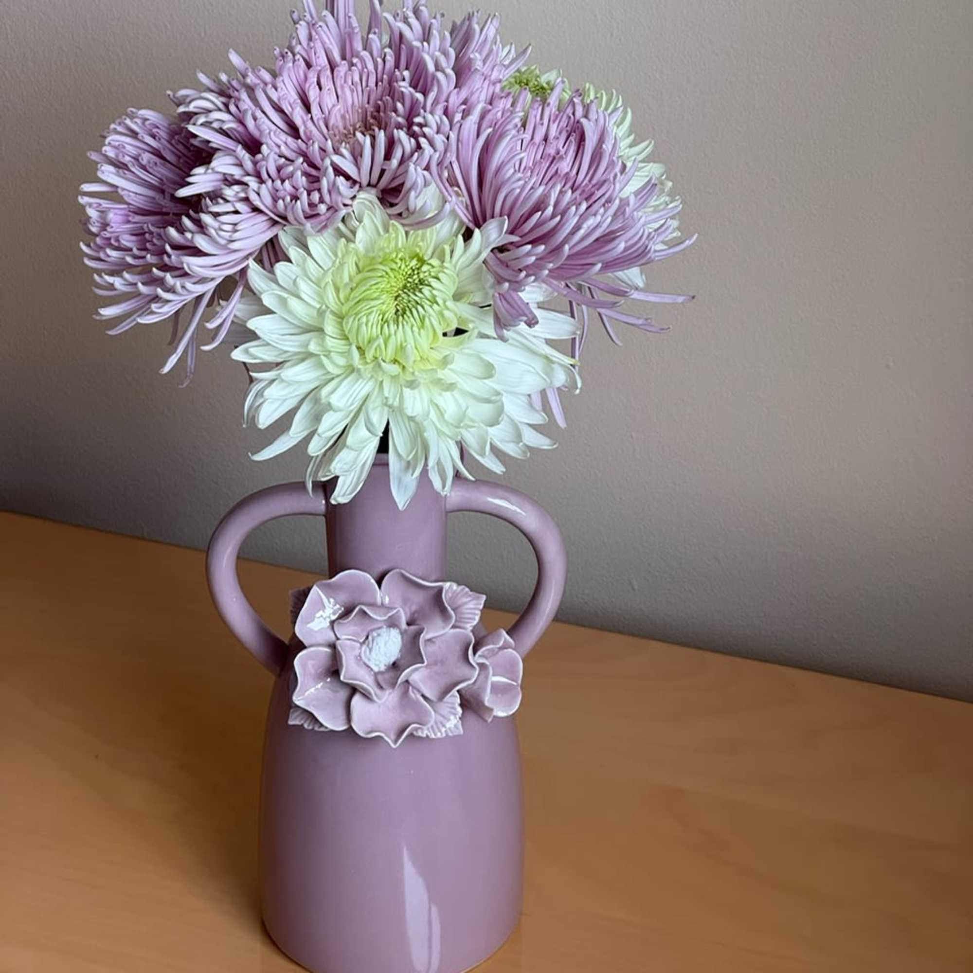 Lavender and white chrysanthemums in a pink vase with handles
