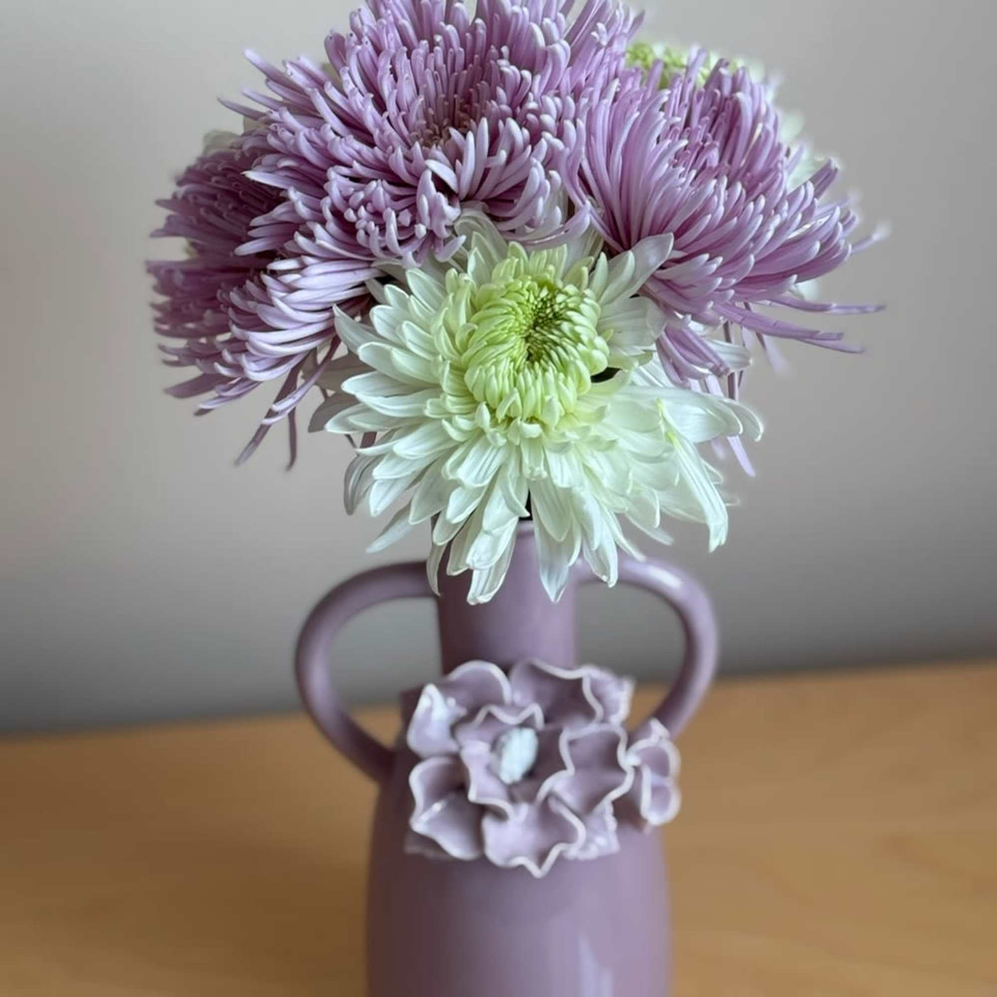 Lavender and white chrysanthemum bouquet in a purple vase