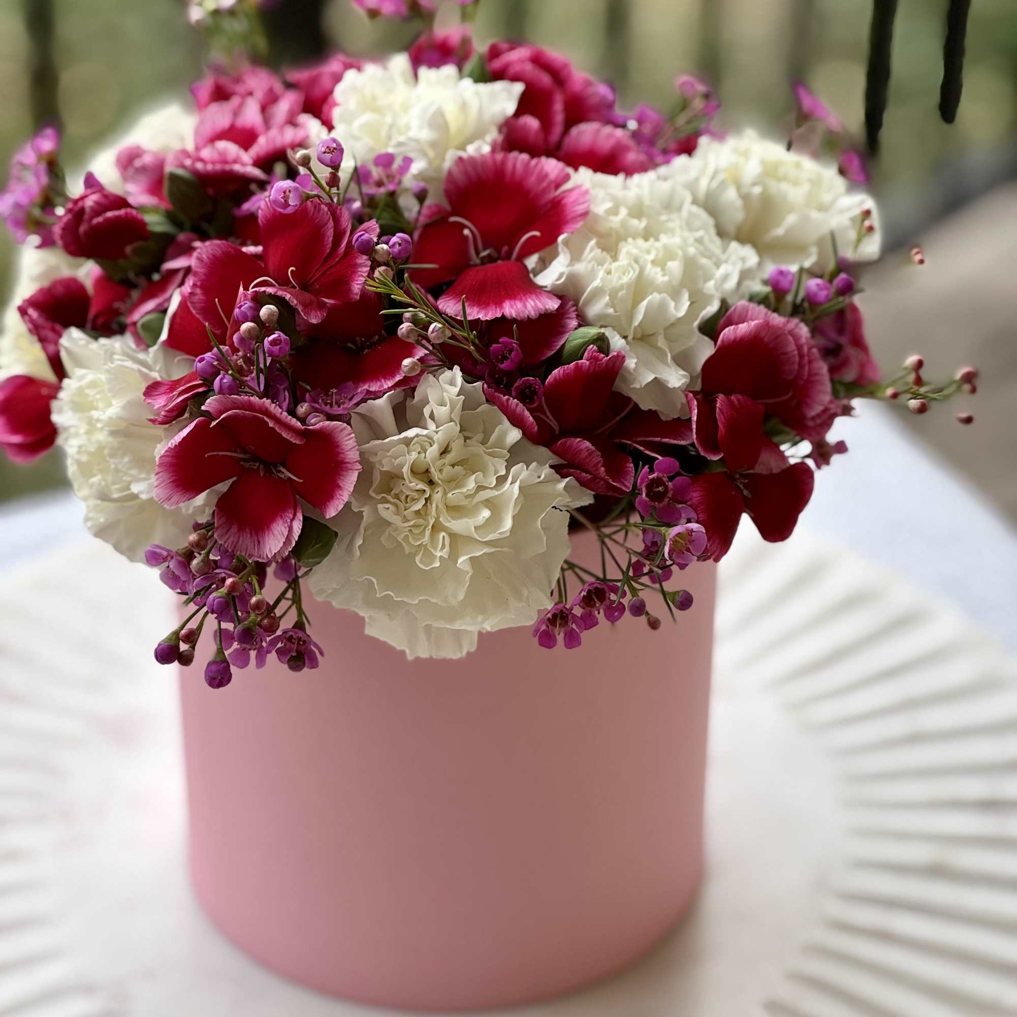 Pink and white carnations in a pink cylindrical box