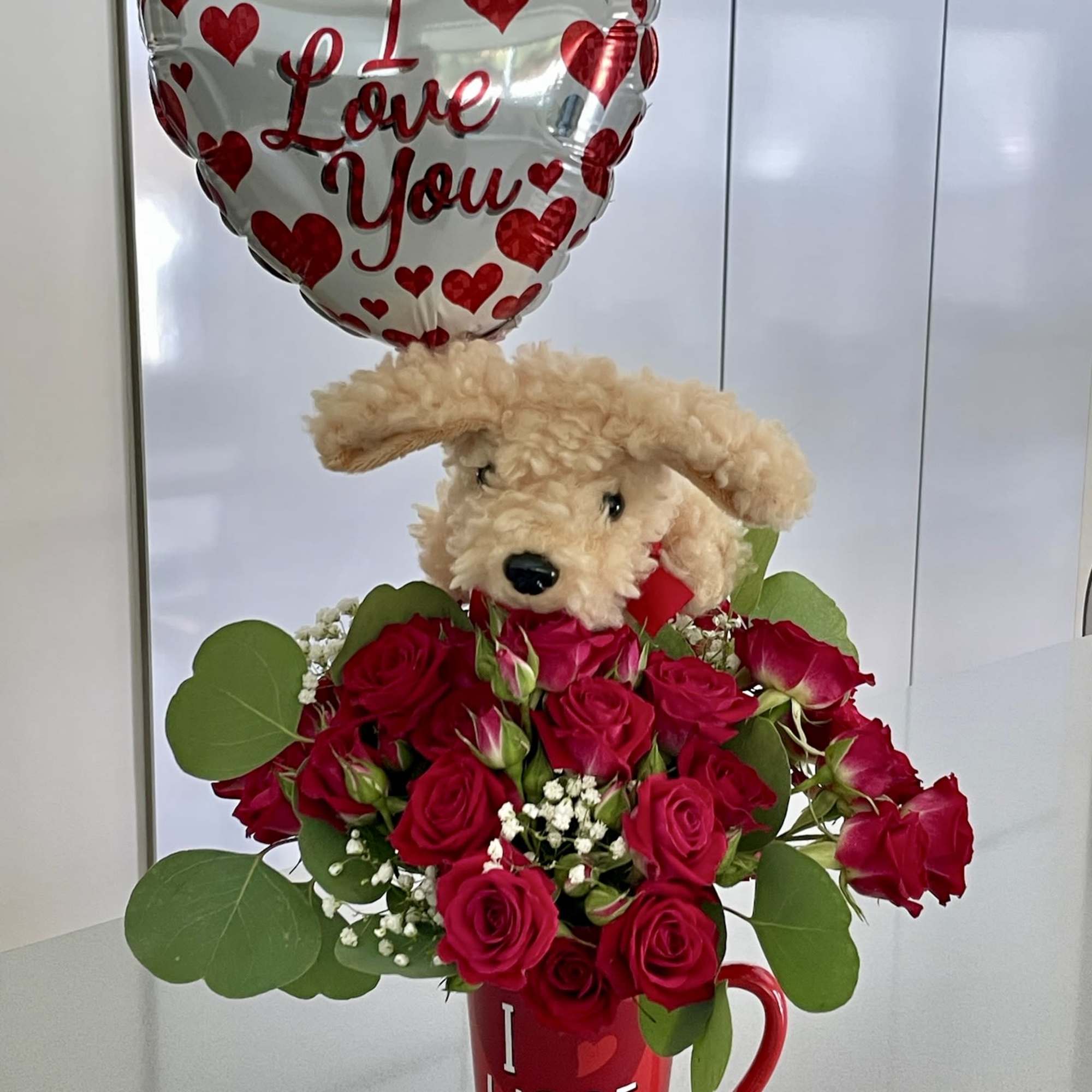 Red rose bouquet with a teddy bear and heart balloon in a mug
