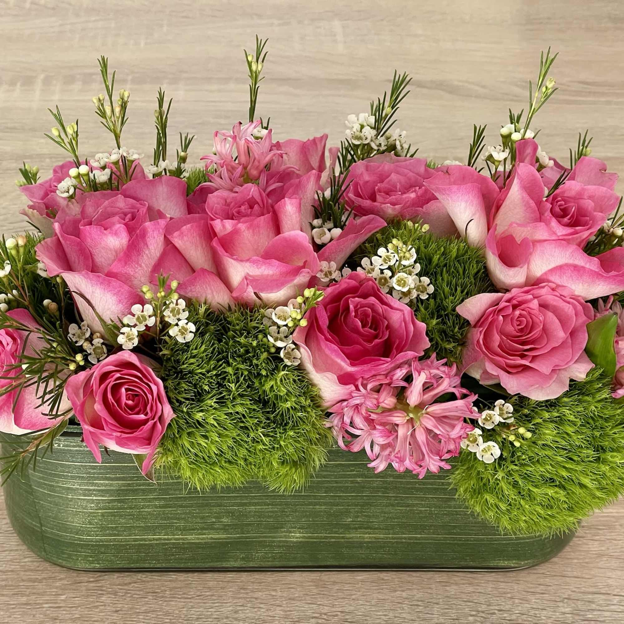 Pink roses and calla lilies in a green rectangular container