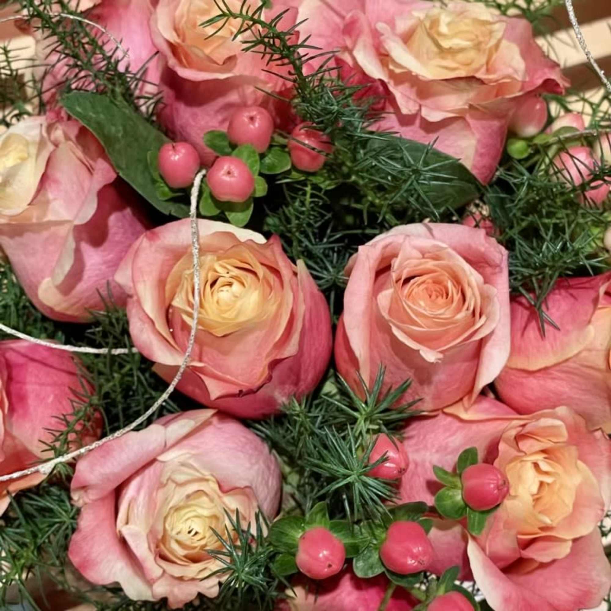 Pink and peach roses with berry accents and greenery