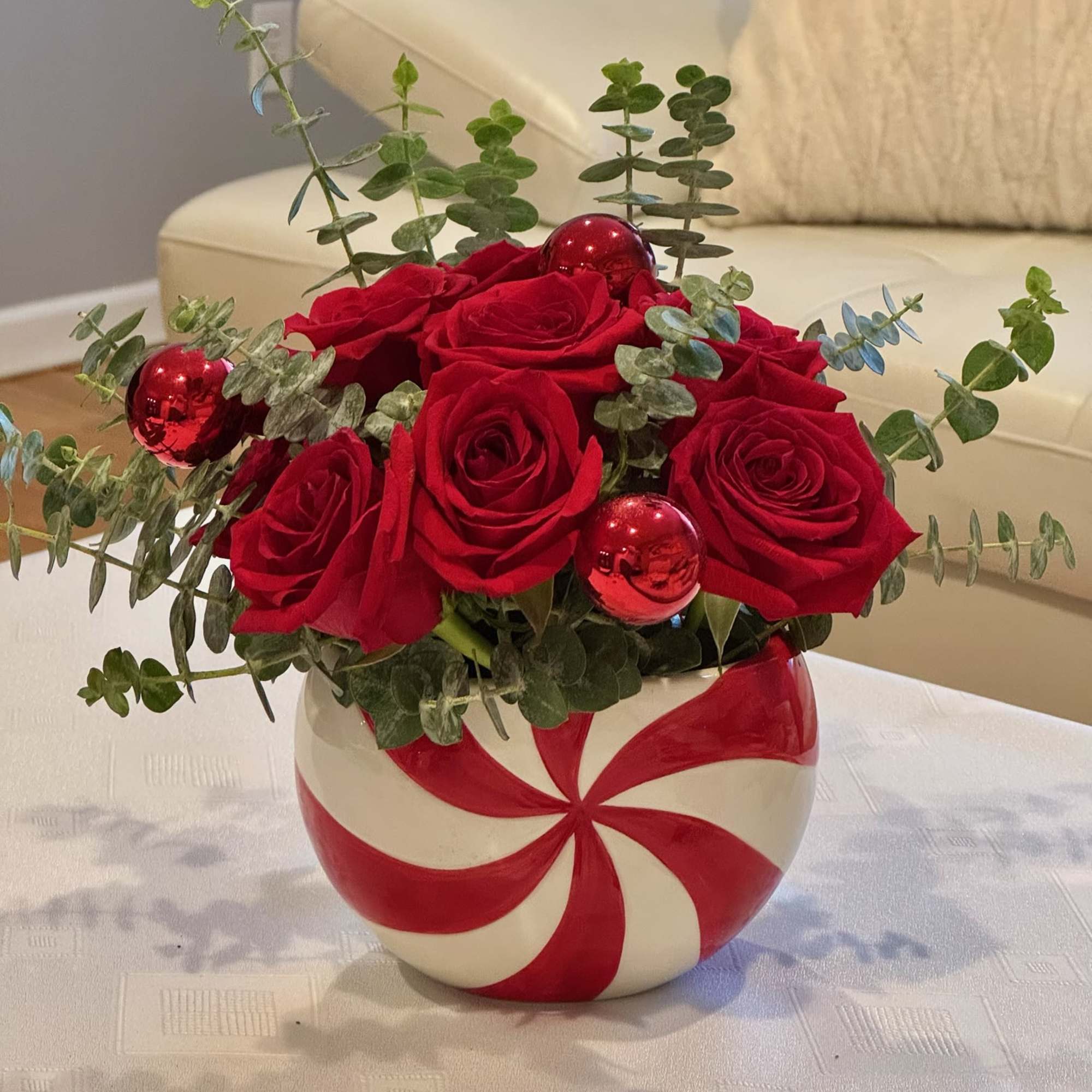 Red roses in a candy cane vase with eucalyptus and red ornaments