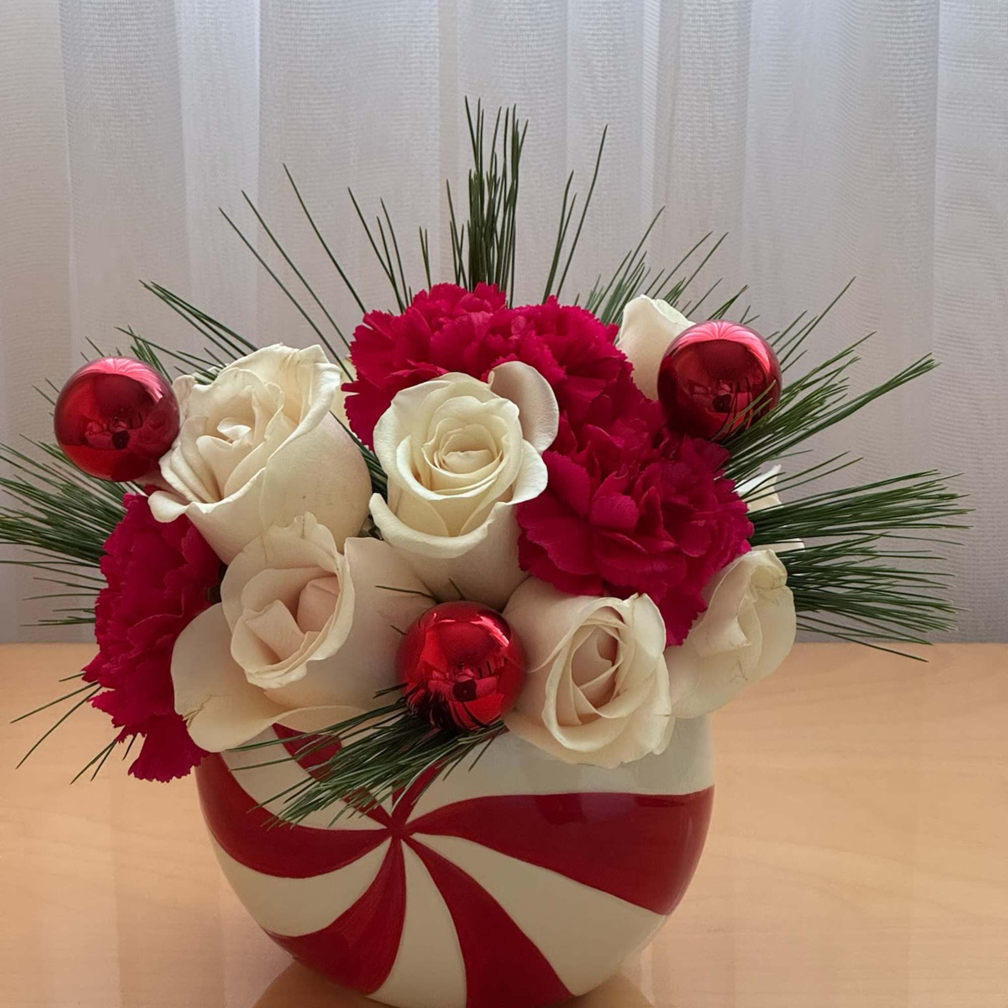 White roses and red carnations in a red-and-white vase with red ornaments