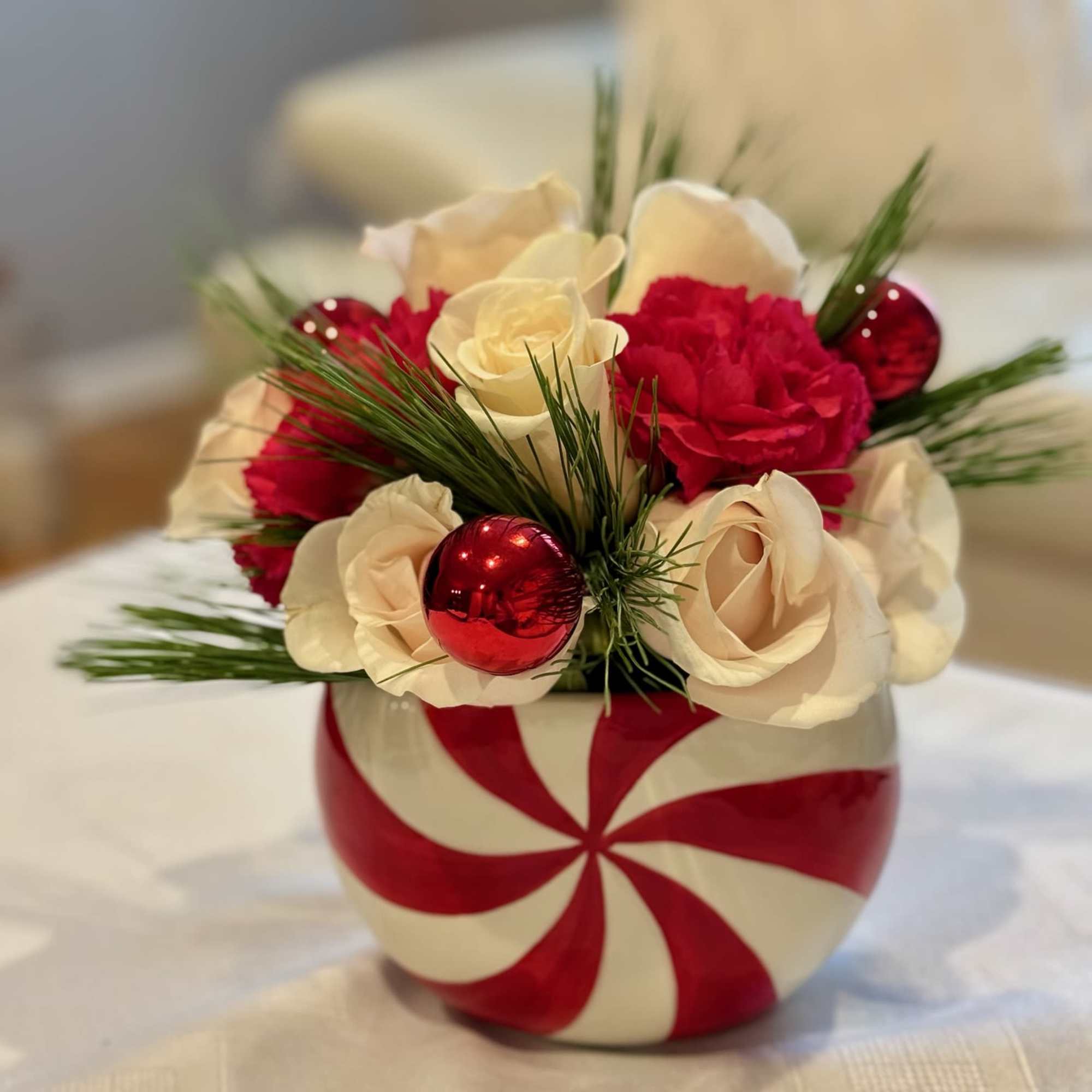 Candy cane vase with red and white roses and holiday ornaments
