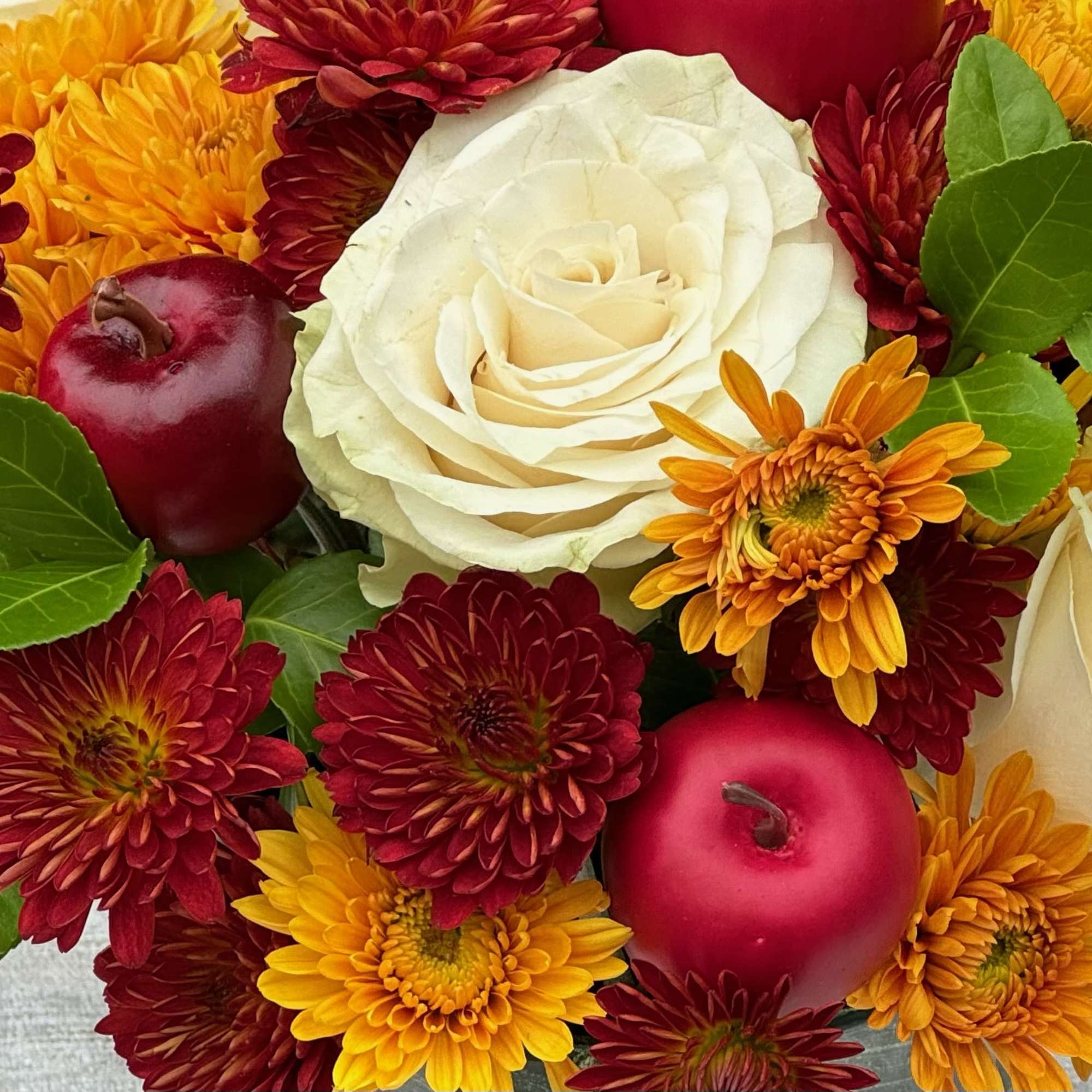 White rose with red and yellow chrysanthemums and red apples