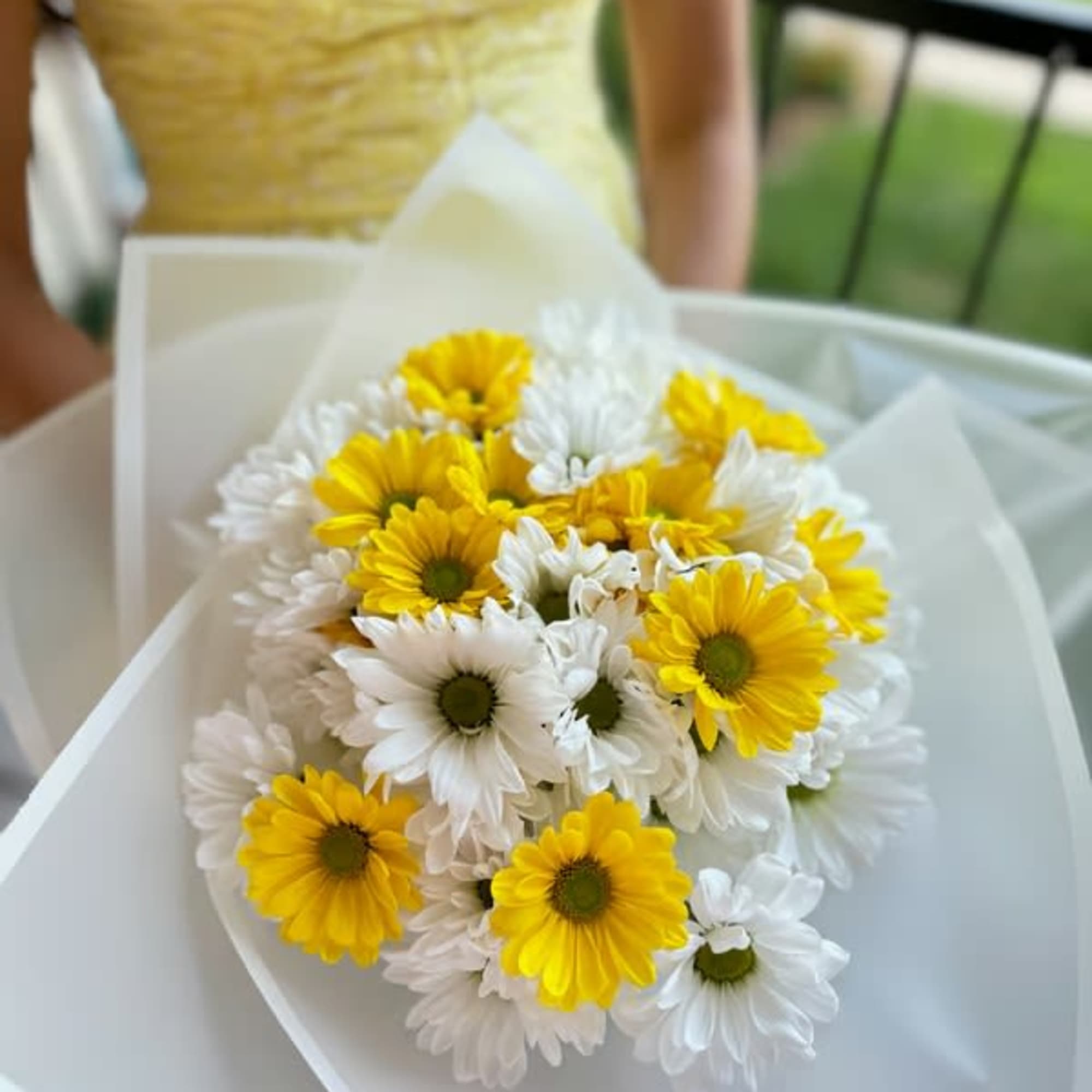 Bouquet of yellow and white daisies wrapped in white paper
