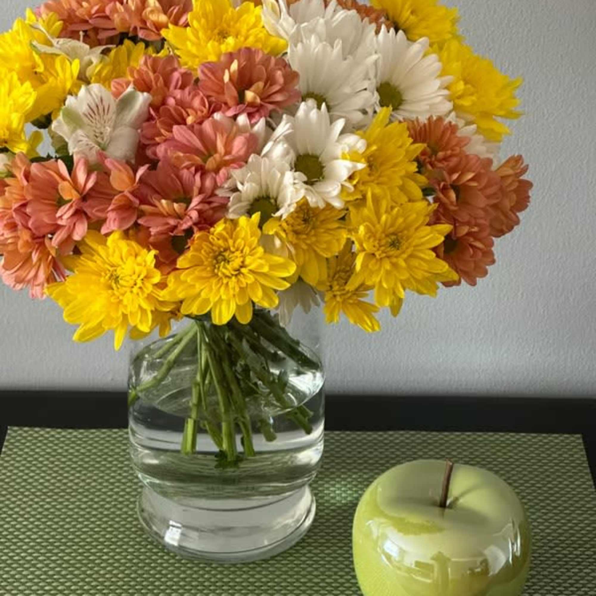 Bouquet of yellow, white, and peach daisies in a clear glass vase