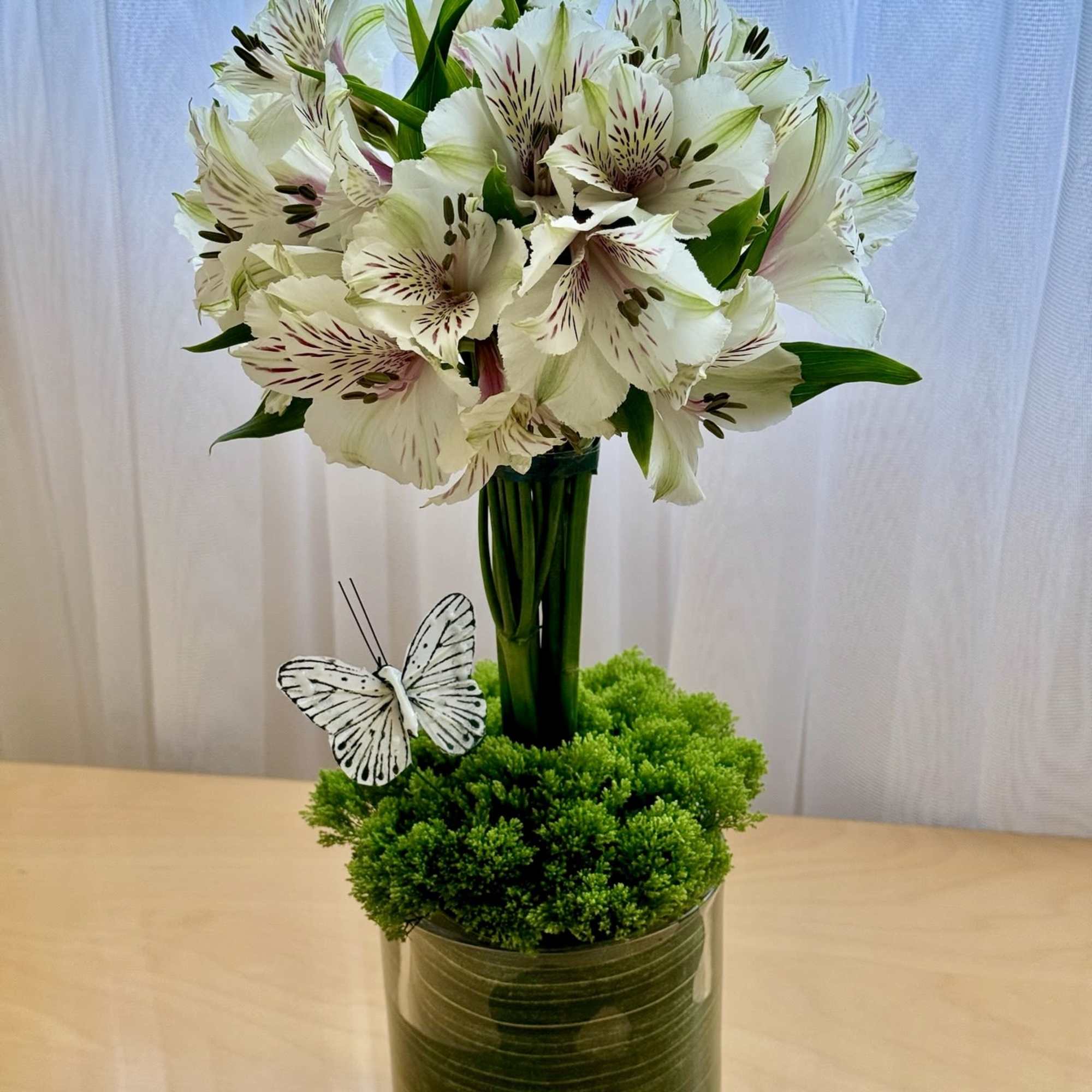 White alstroemeria bouquet in a glass vase with a butterfly decoration