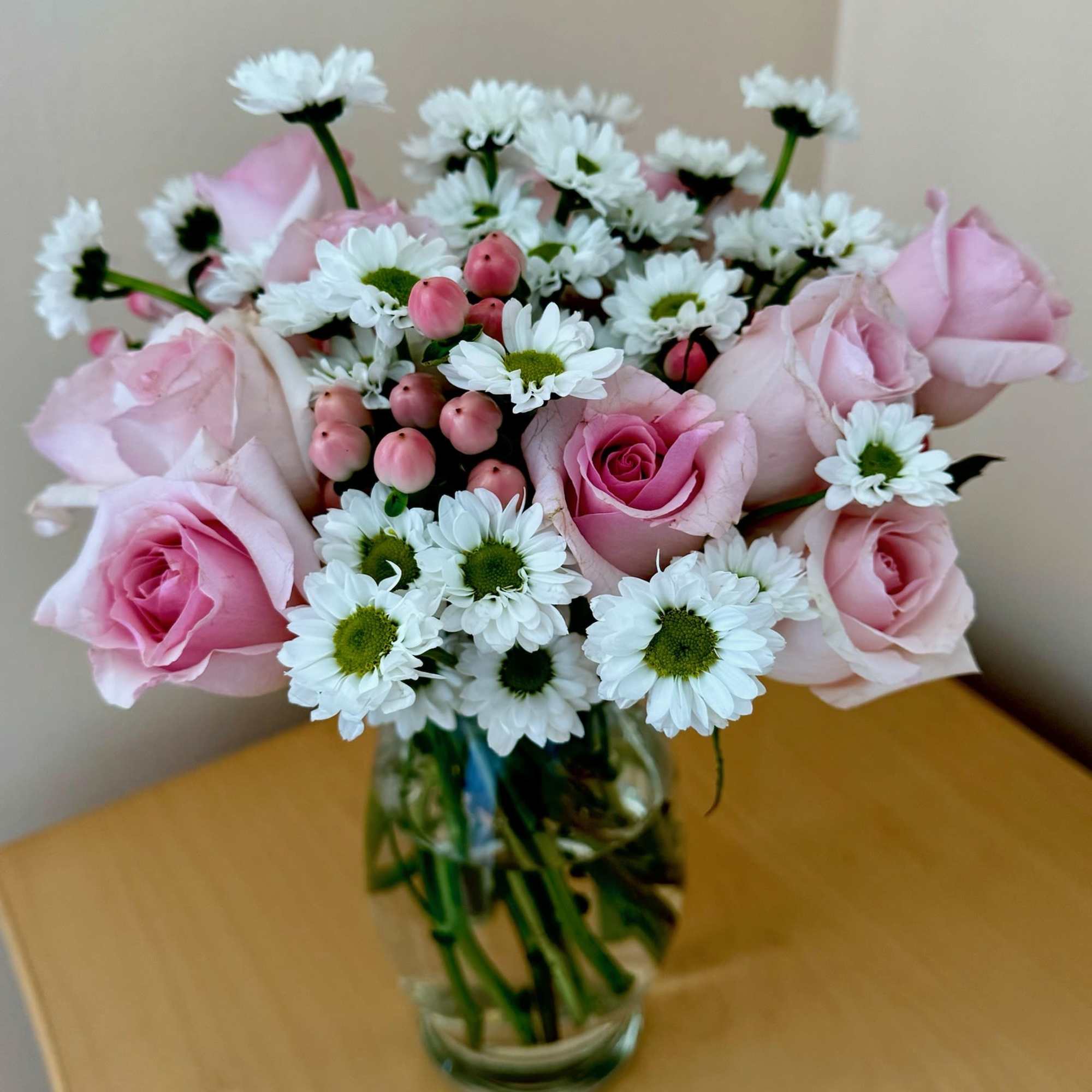 Pink roses and white daisies arranged in a clear glass vase