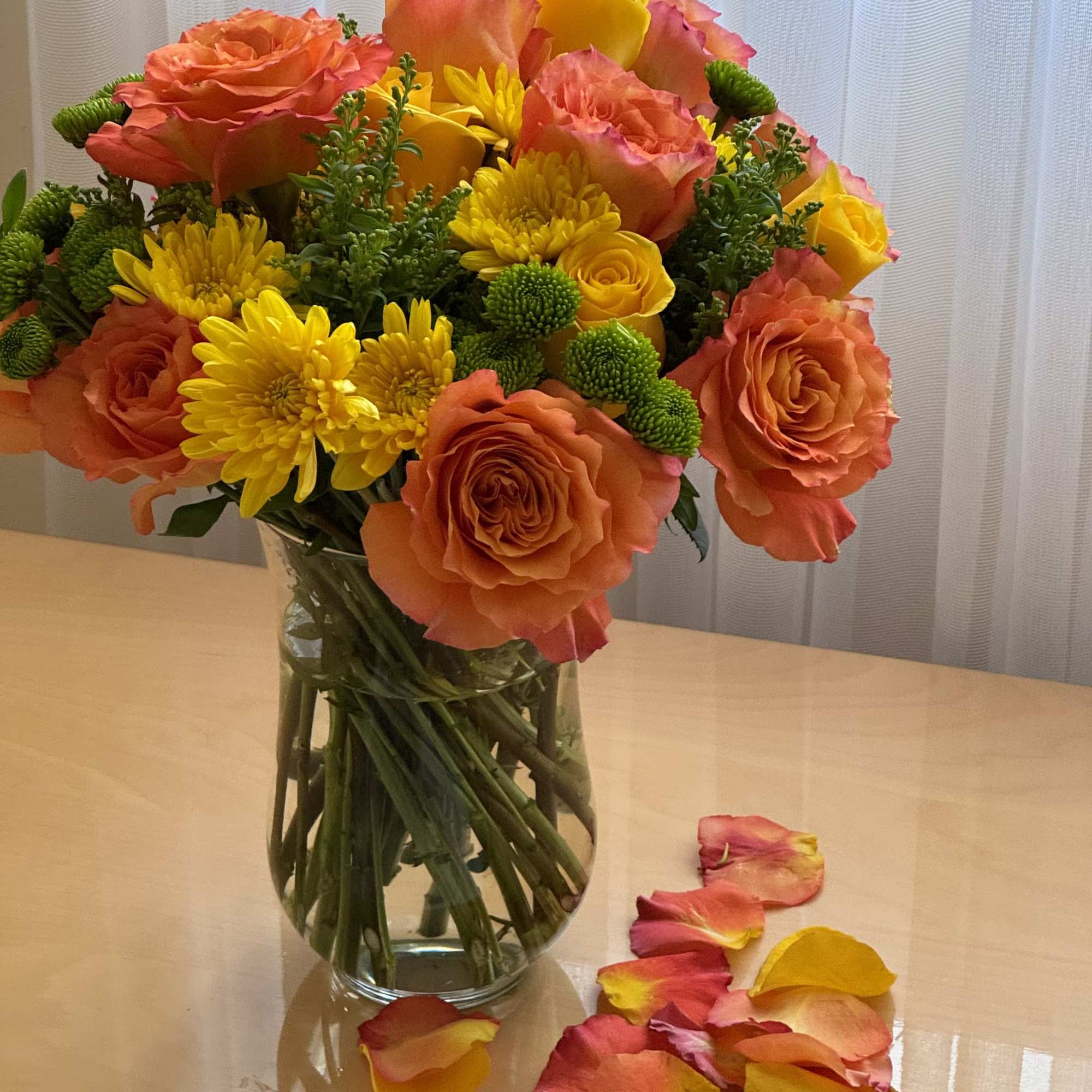 Bouquet of orange roses and yellow daisies in a glass vase