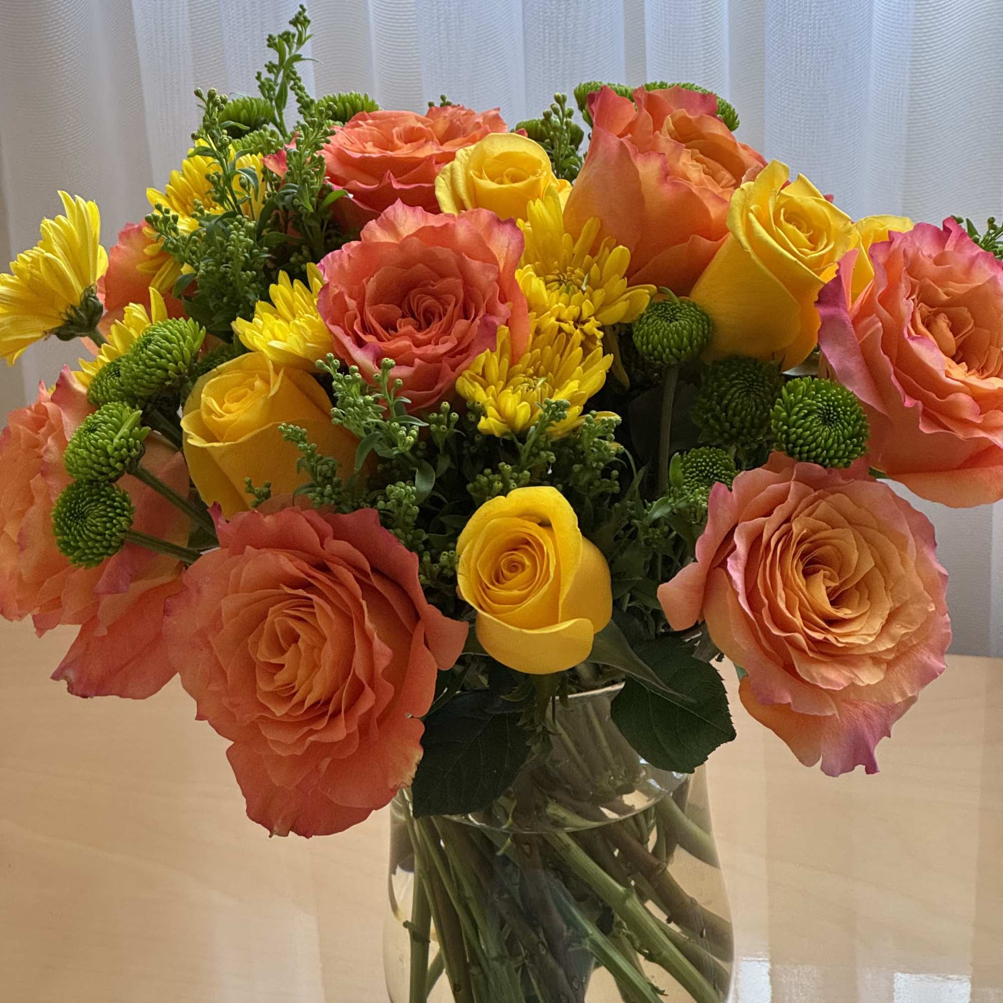 Bouquet of orange and yellow roses in a clear glass vase
