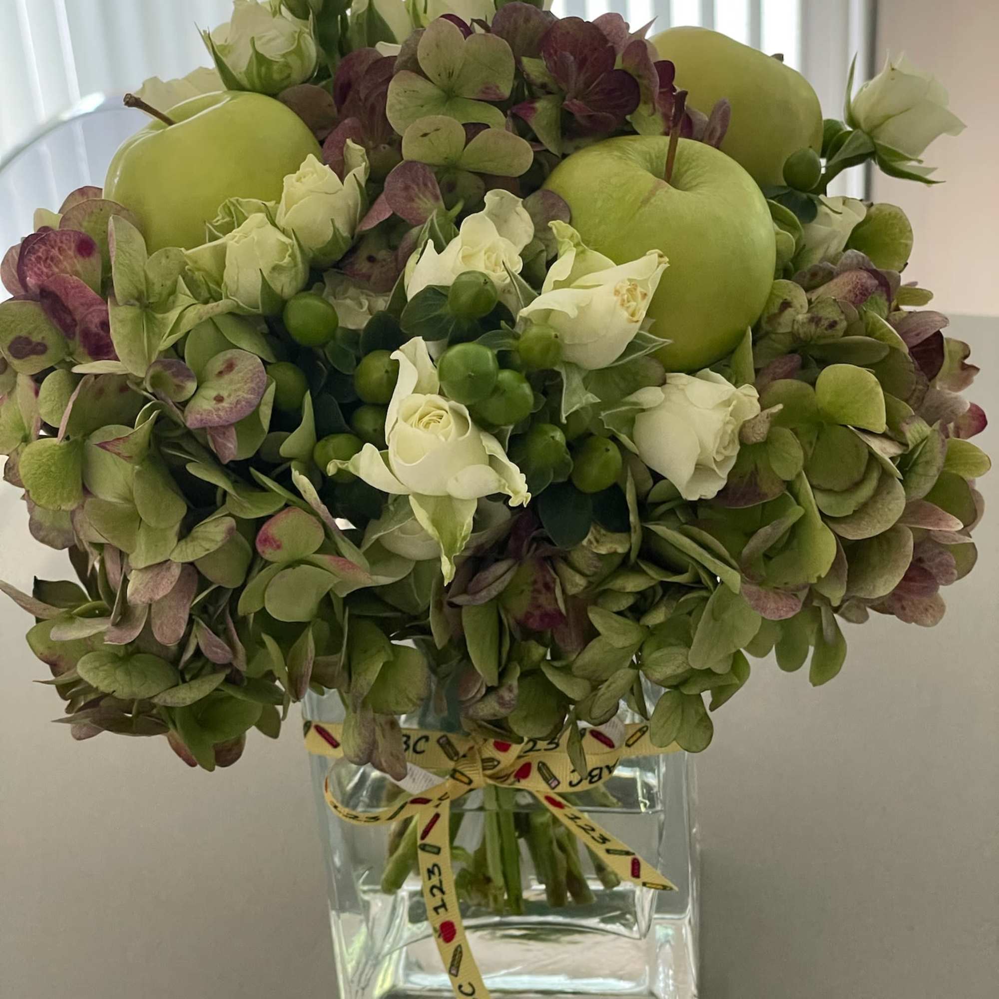 Green hydrangea and white rose arrangement in a clear square vase