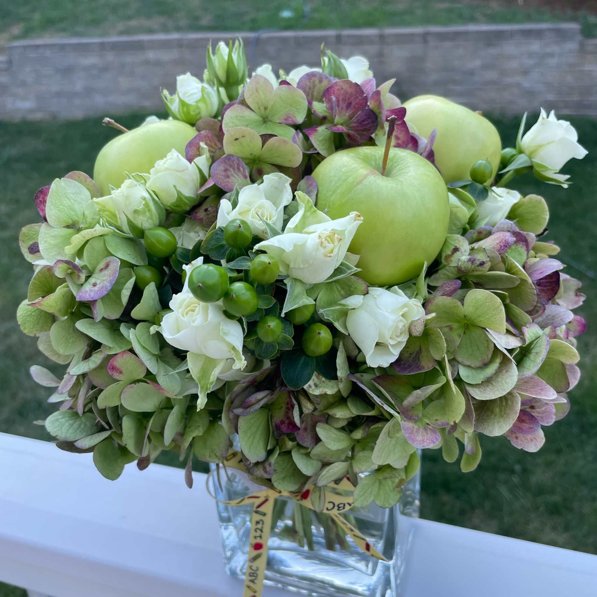 Hydrangea bouquet with green apples in a glass vase