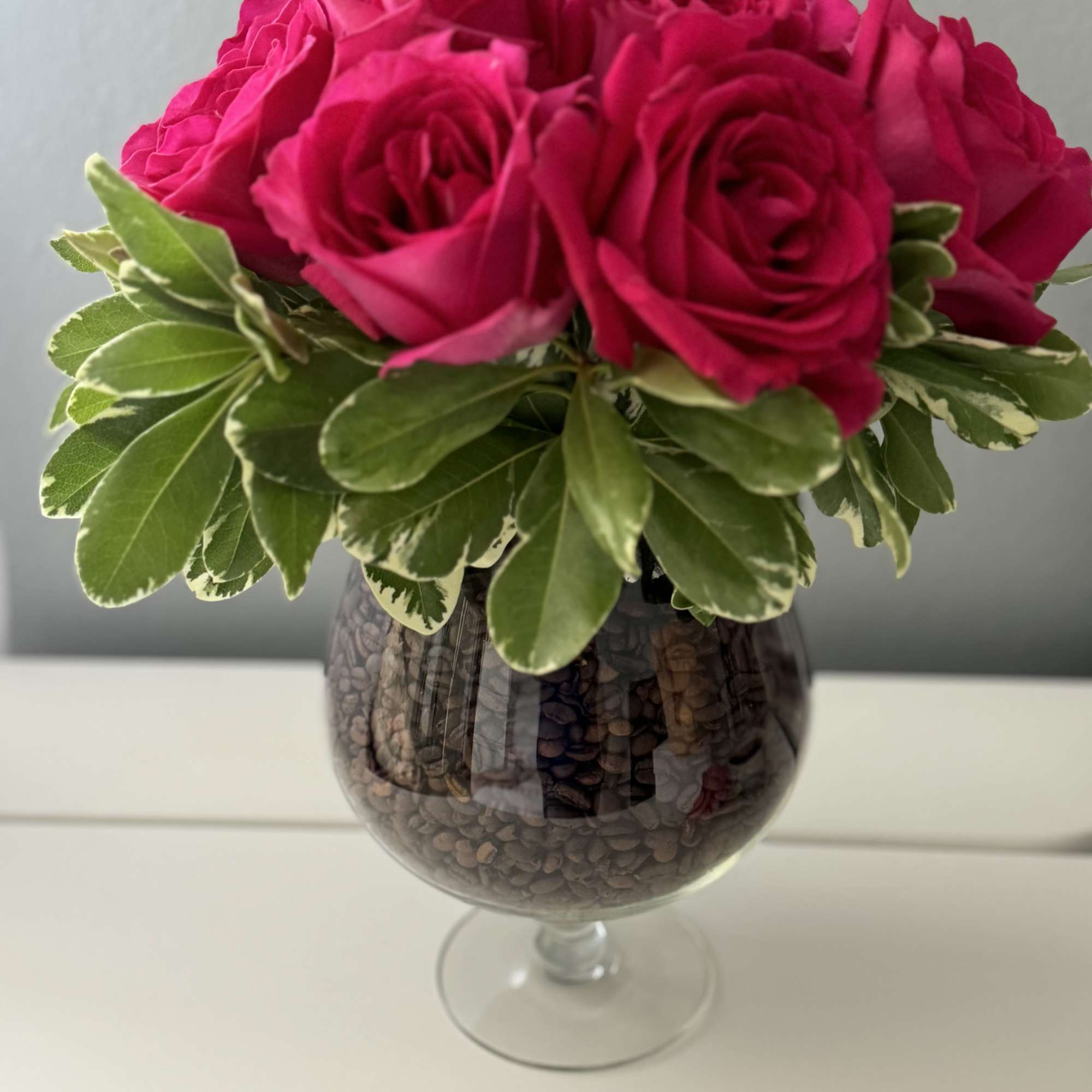Hot pink roses arranged in a glass goblet vase