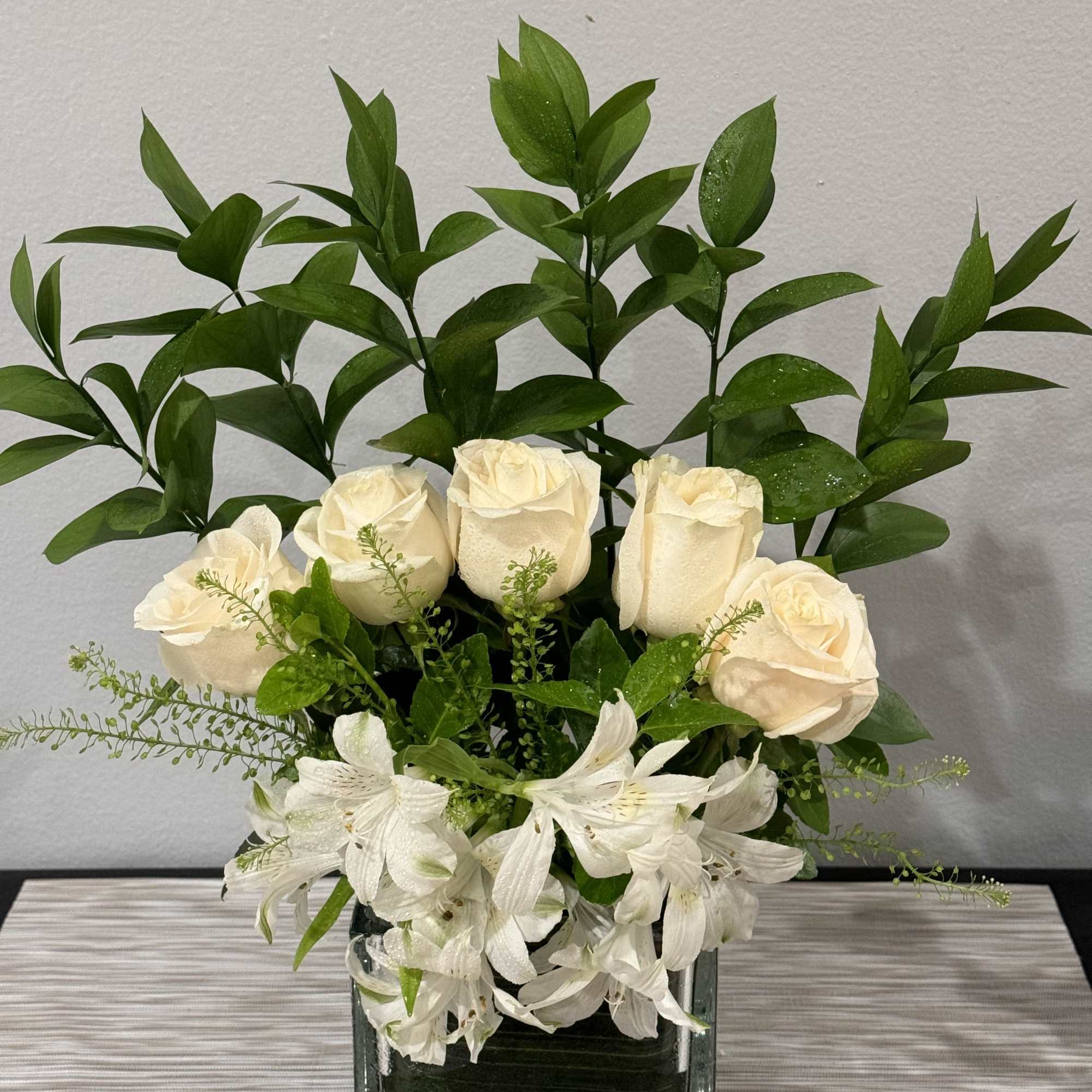 White roses and alstroemeria in a square glass vase