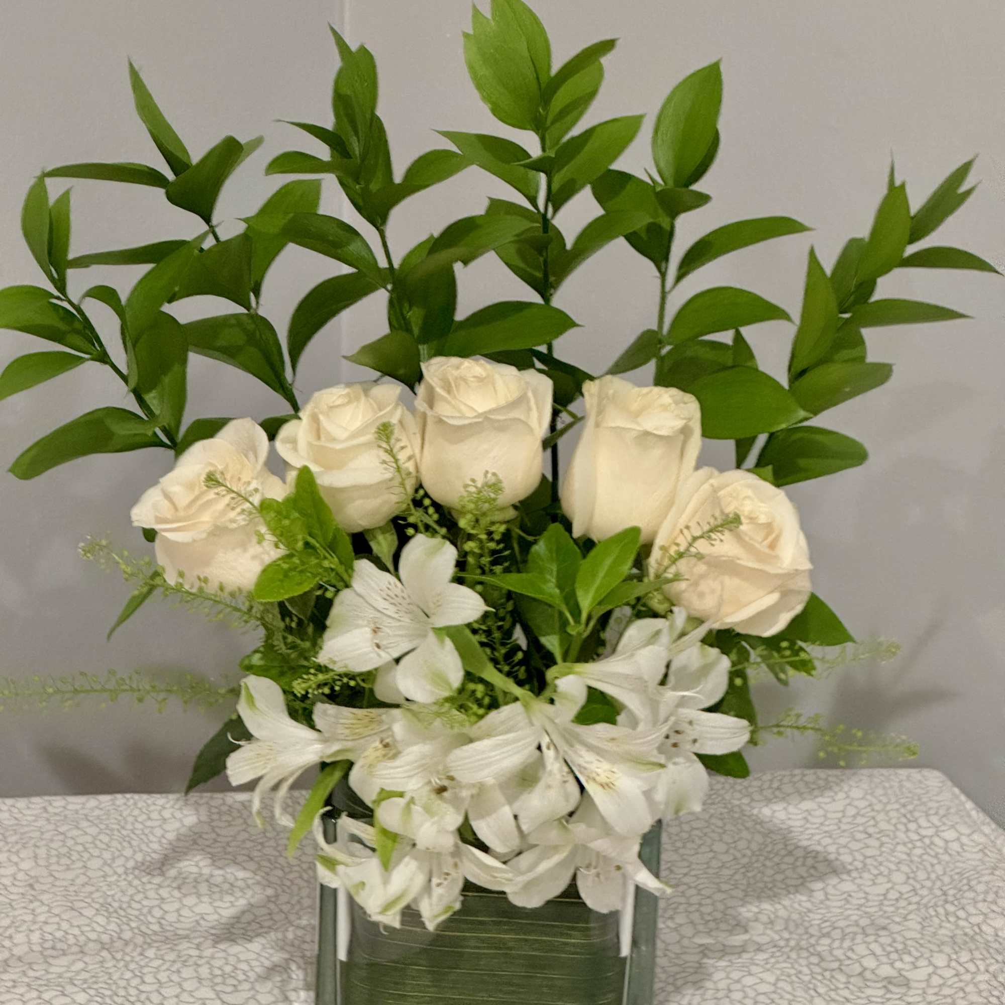 White roses and alstroemeria in a square glass vase