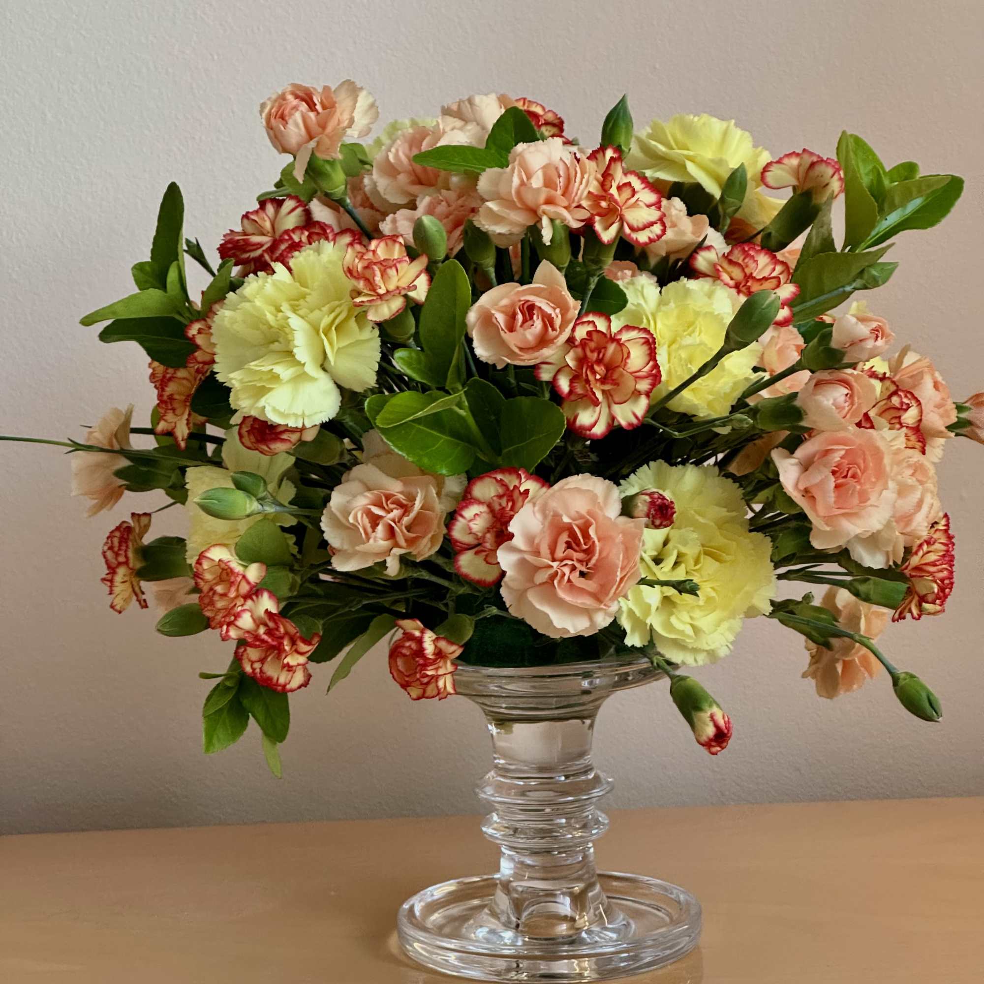 Mixed carnations and peach spray roses in a clear glass vase