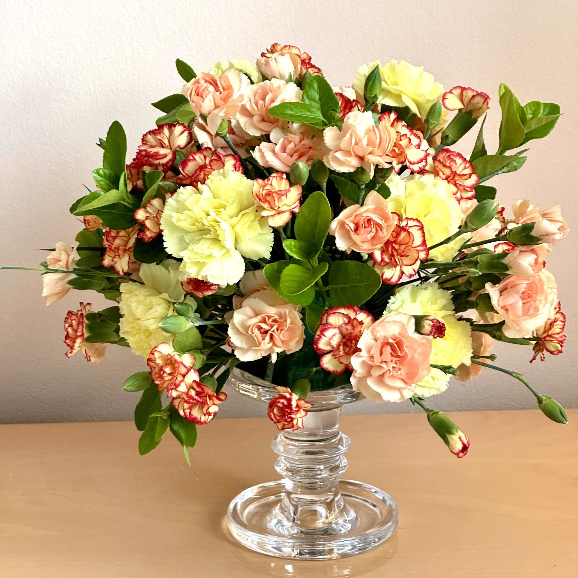 Mixed bouquet of carnations in a clear glass pedestal vase