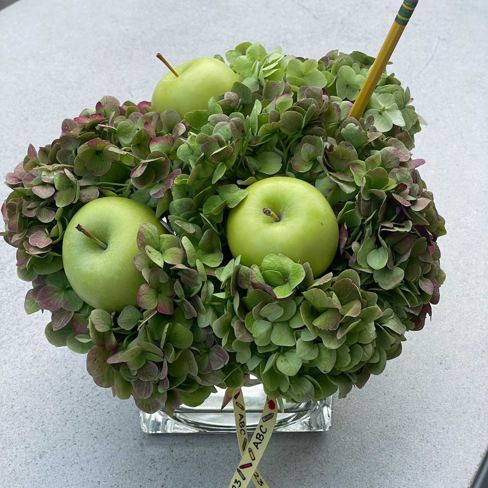 Hydrangea arrangement with green apples in a glass vase