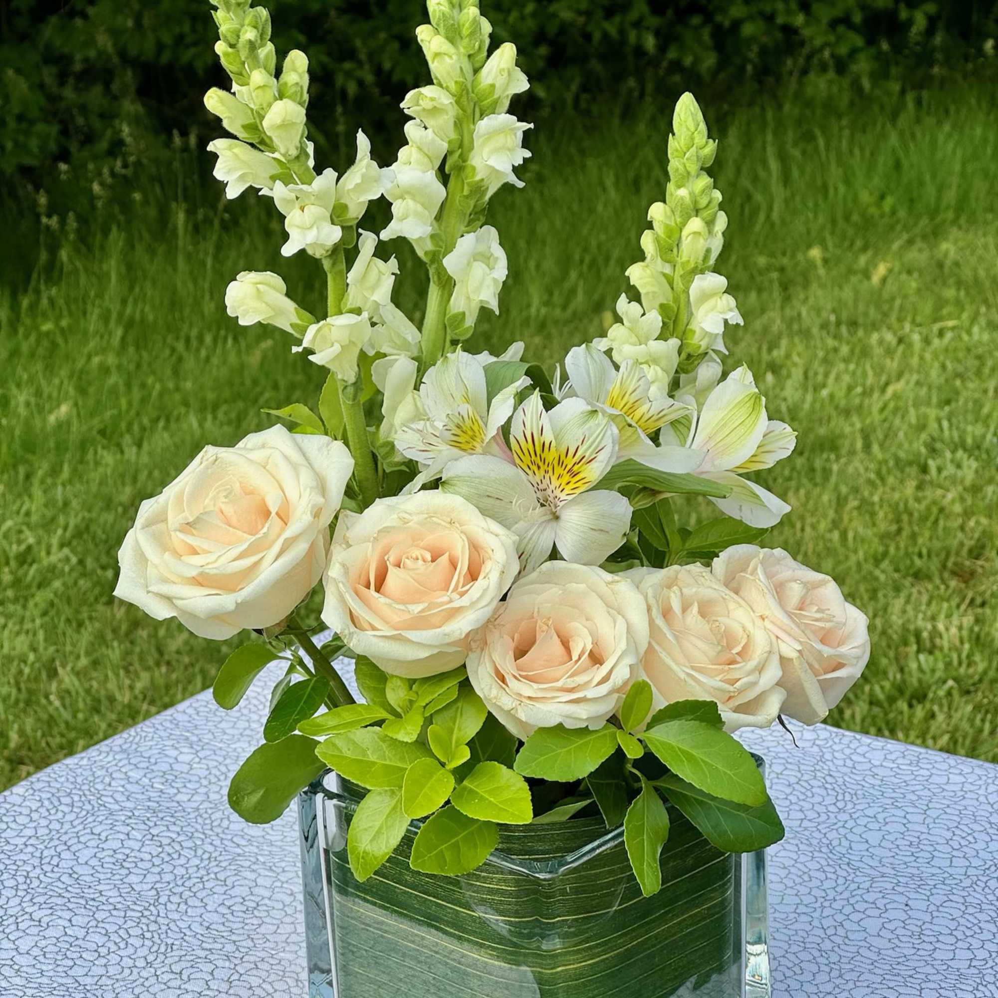 Cream roses and white snapdragons in a glass vase