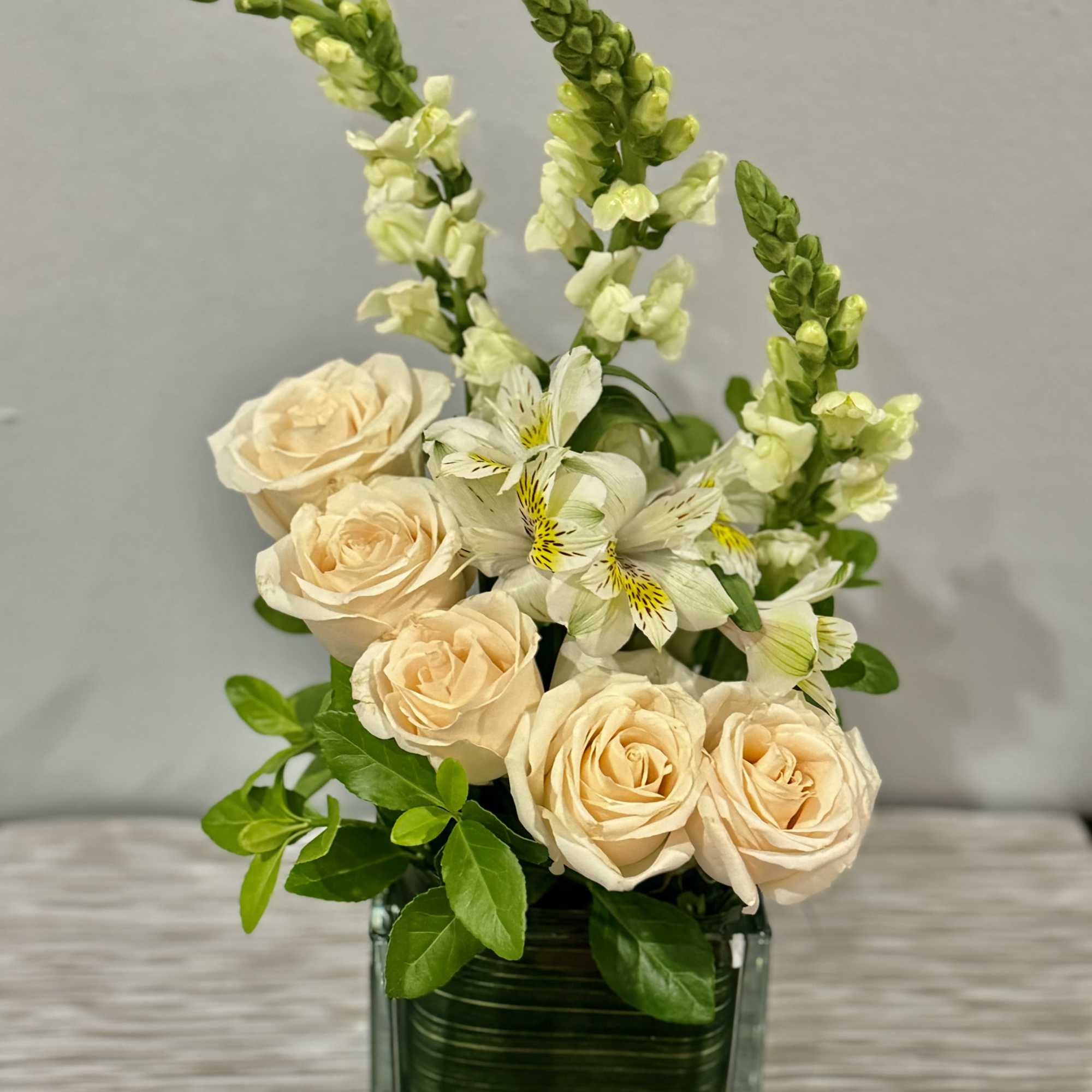 Peach roses and white alstroemeria in a square glass vase