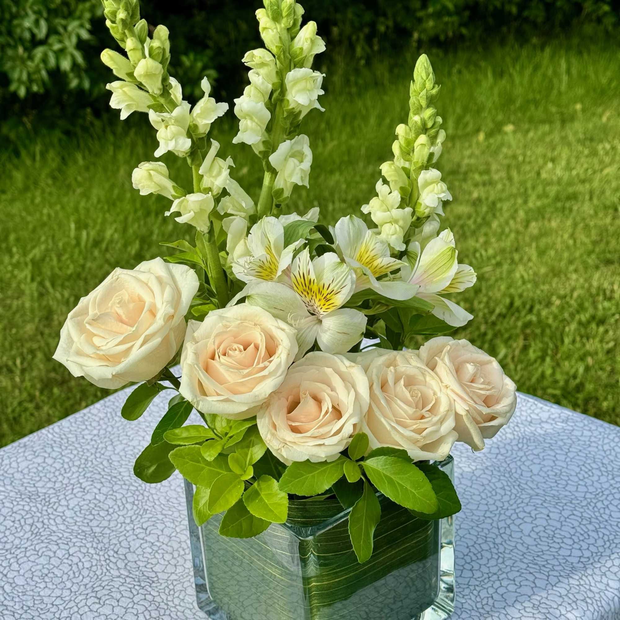 Cream roses and white snapdragons in a clear glass vase