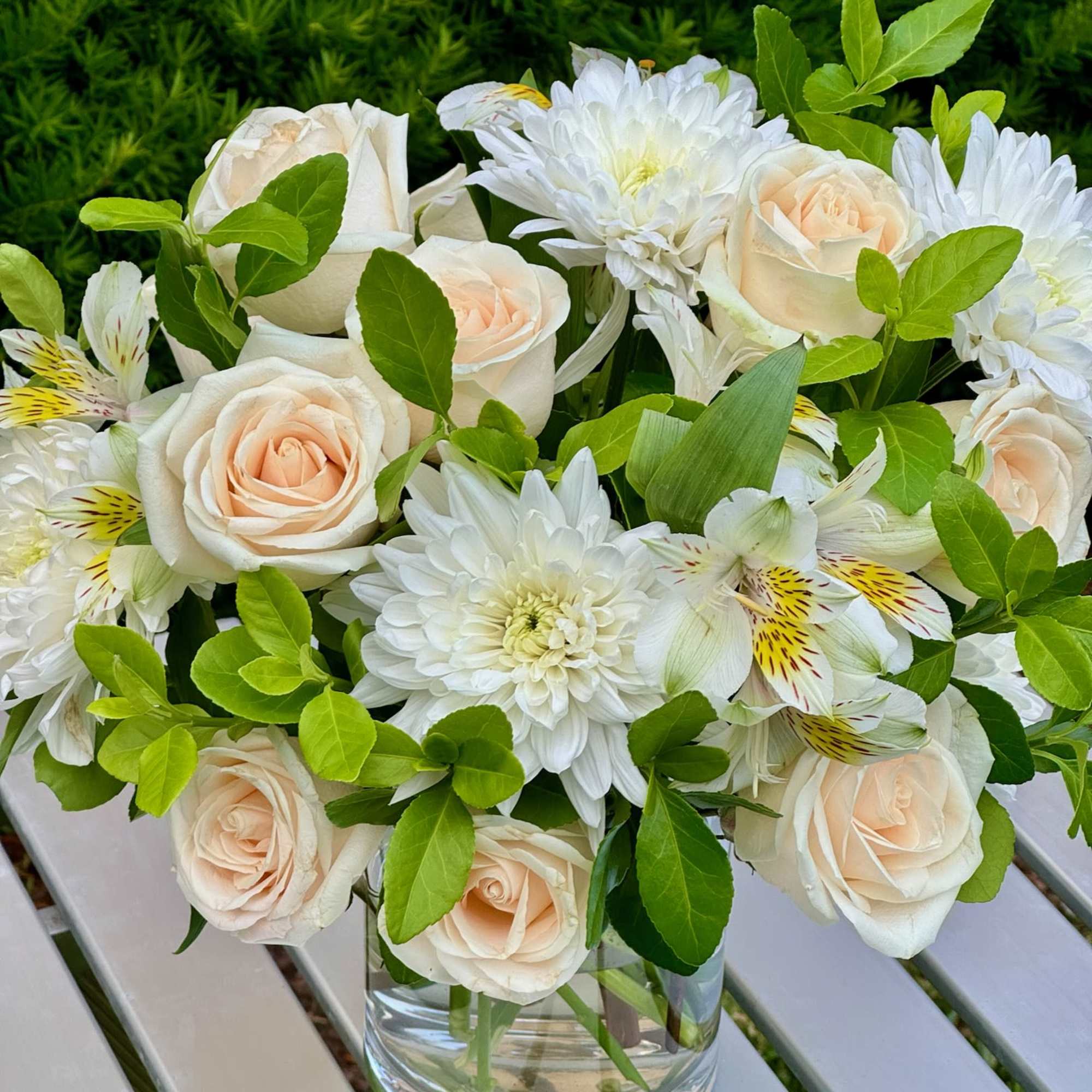 Cream roses and white daisies in a clear glass vase