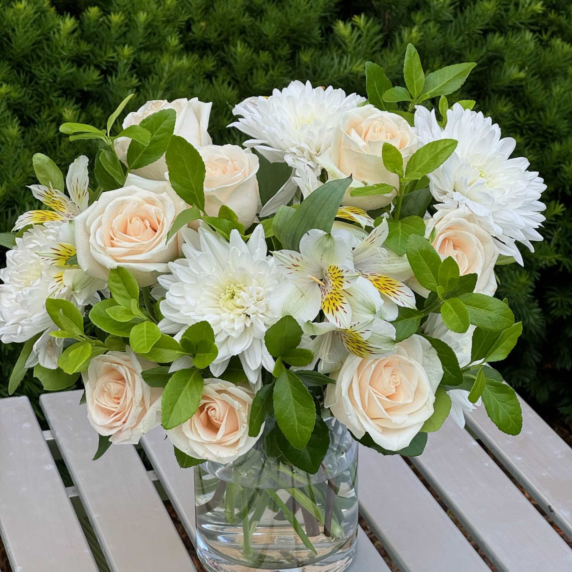 Bouquet of cream roses and white daisies in a clear glass vase