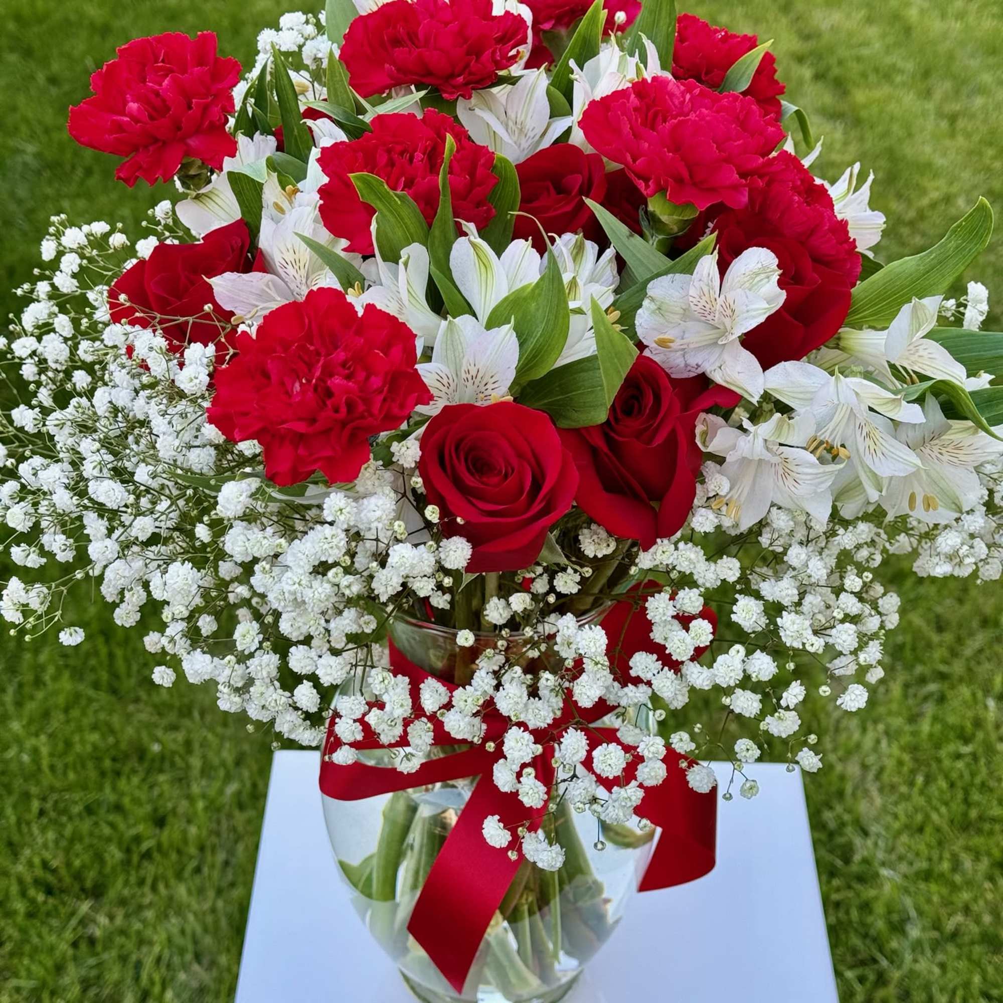 Red roses and carnations with white alstroemeria in a glass vase